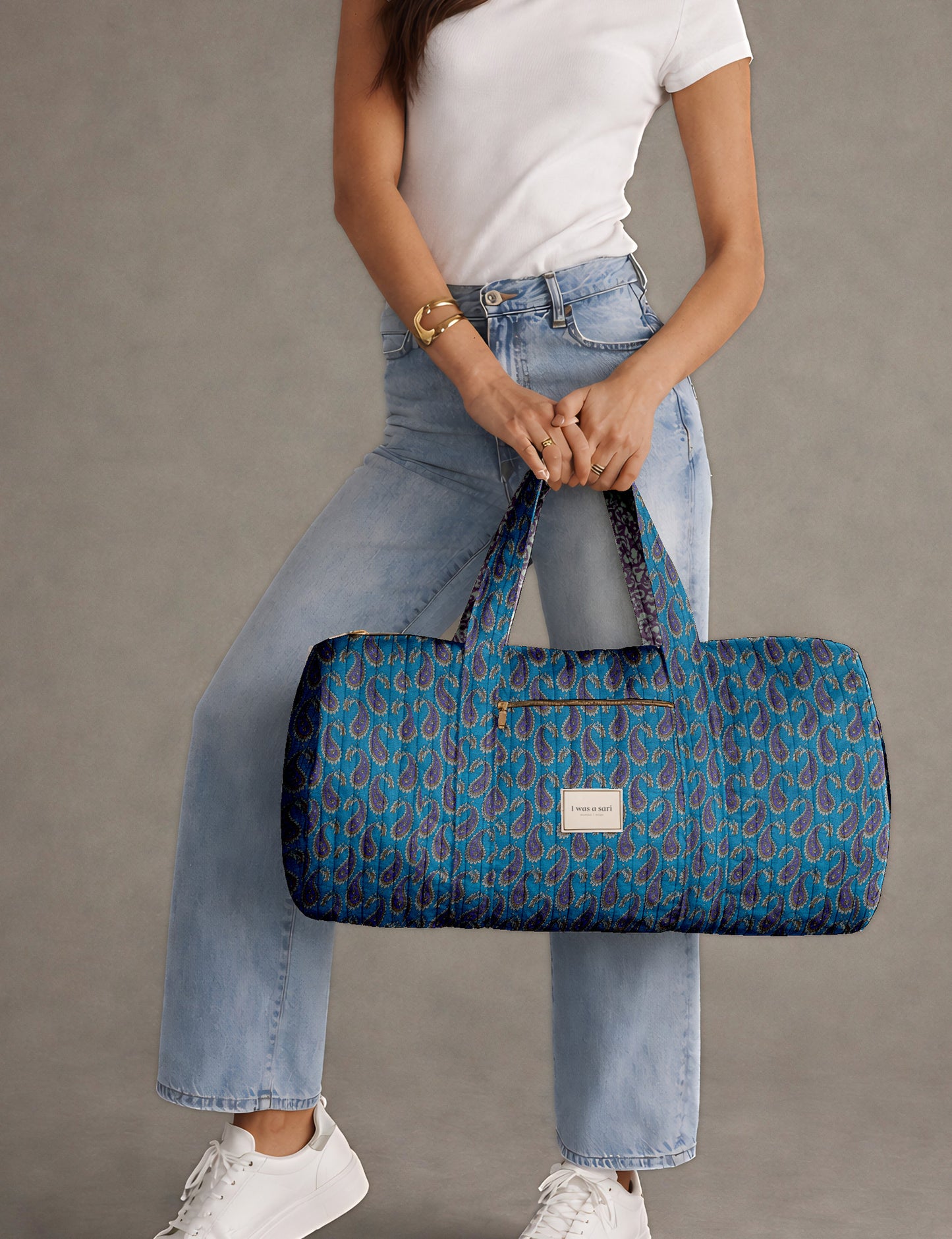 Brown paisley quilted bowling bag with dual handles, front zipper pocket, and "I was a sari" label on front side