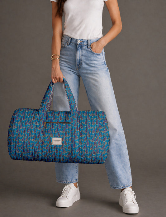 Quilted brown paisley barrel bag with double handles, front pocket, and gold zipper, shown in side angle view