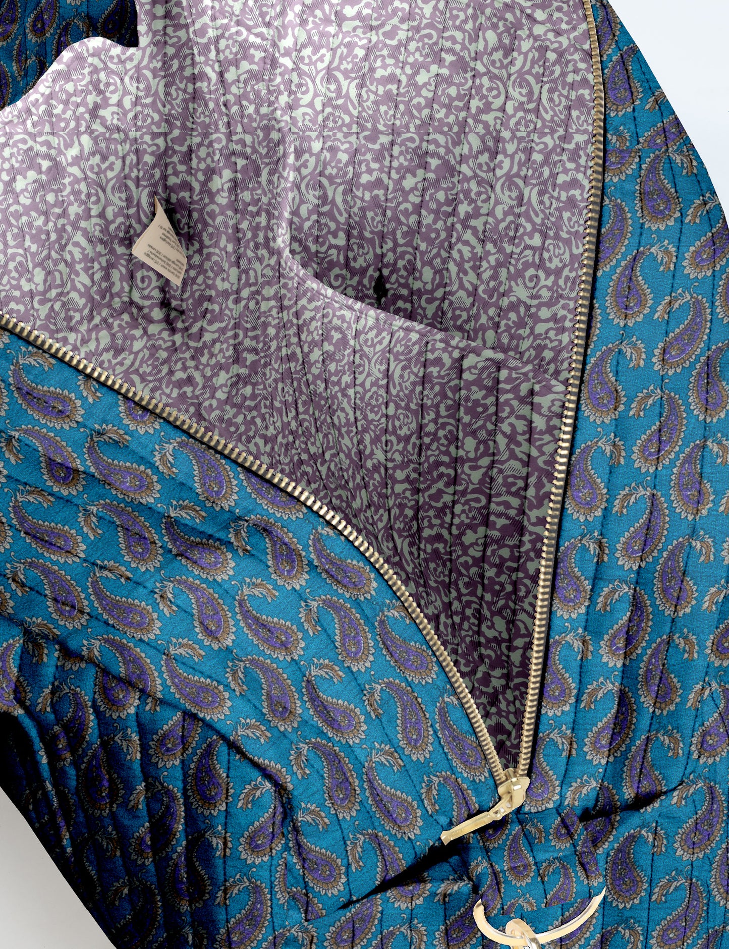 Brown quilted duffle bag with paisley pattern, front zip pocket, dual handles, and label reading "I was a sari"