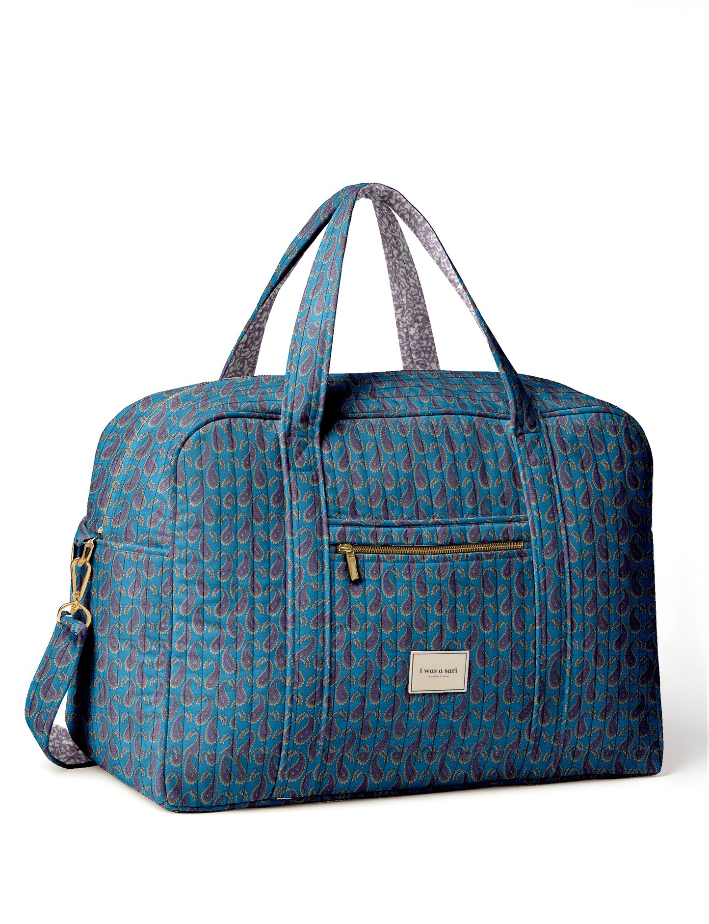 Brown quilted duffle bag with paisley pattern, front zip pocket, dual handles, and label reading "I was a sari"