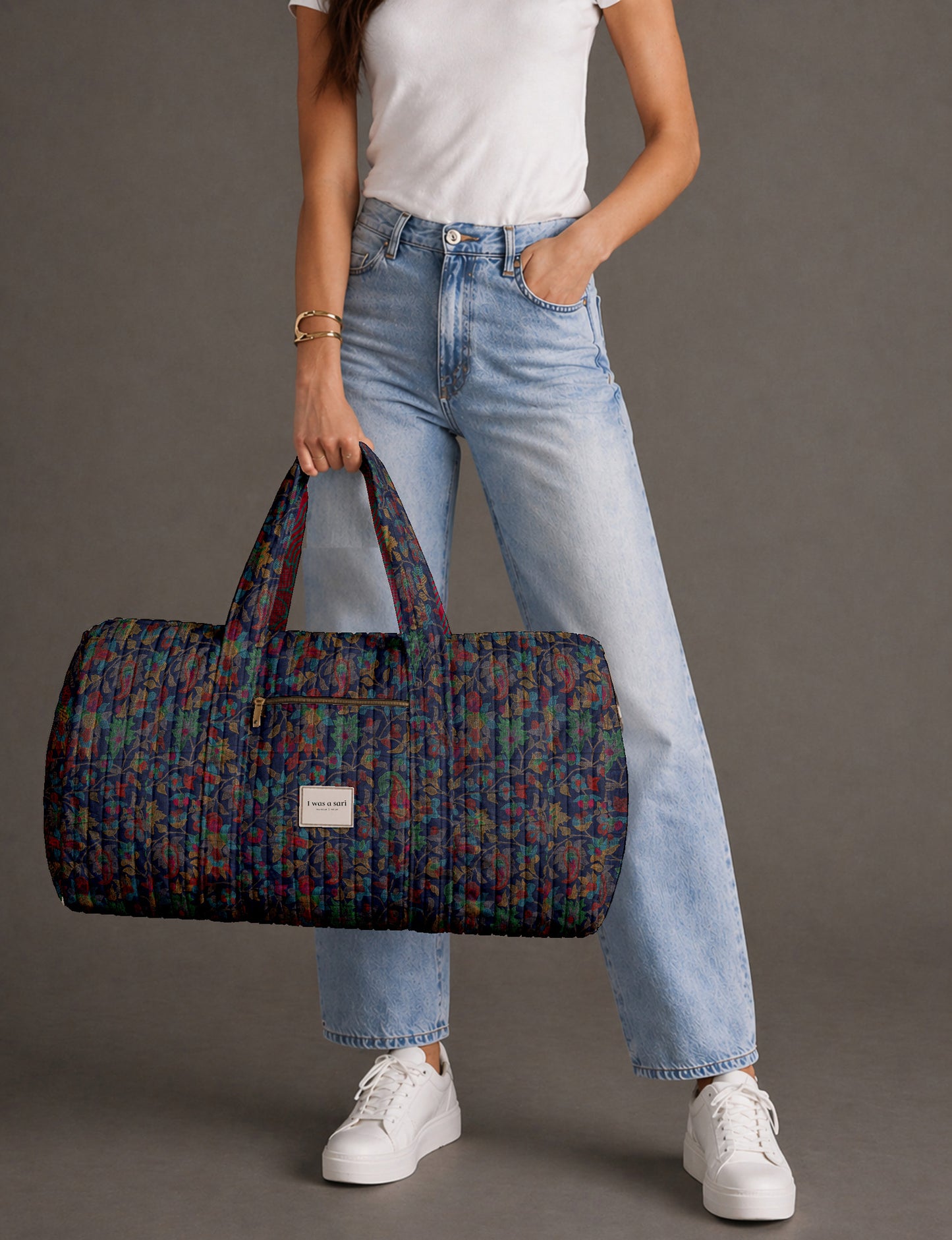 Quilted brown paisley barrel bag with double handles, front pocket, and gold zipper, shown in side angle view