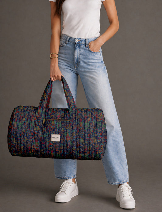 Quilted brown paisley barrel bag with double handles, front pocket, and gold zipper, shown in side angle view