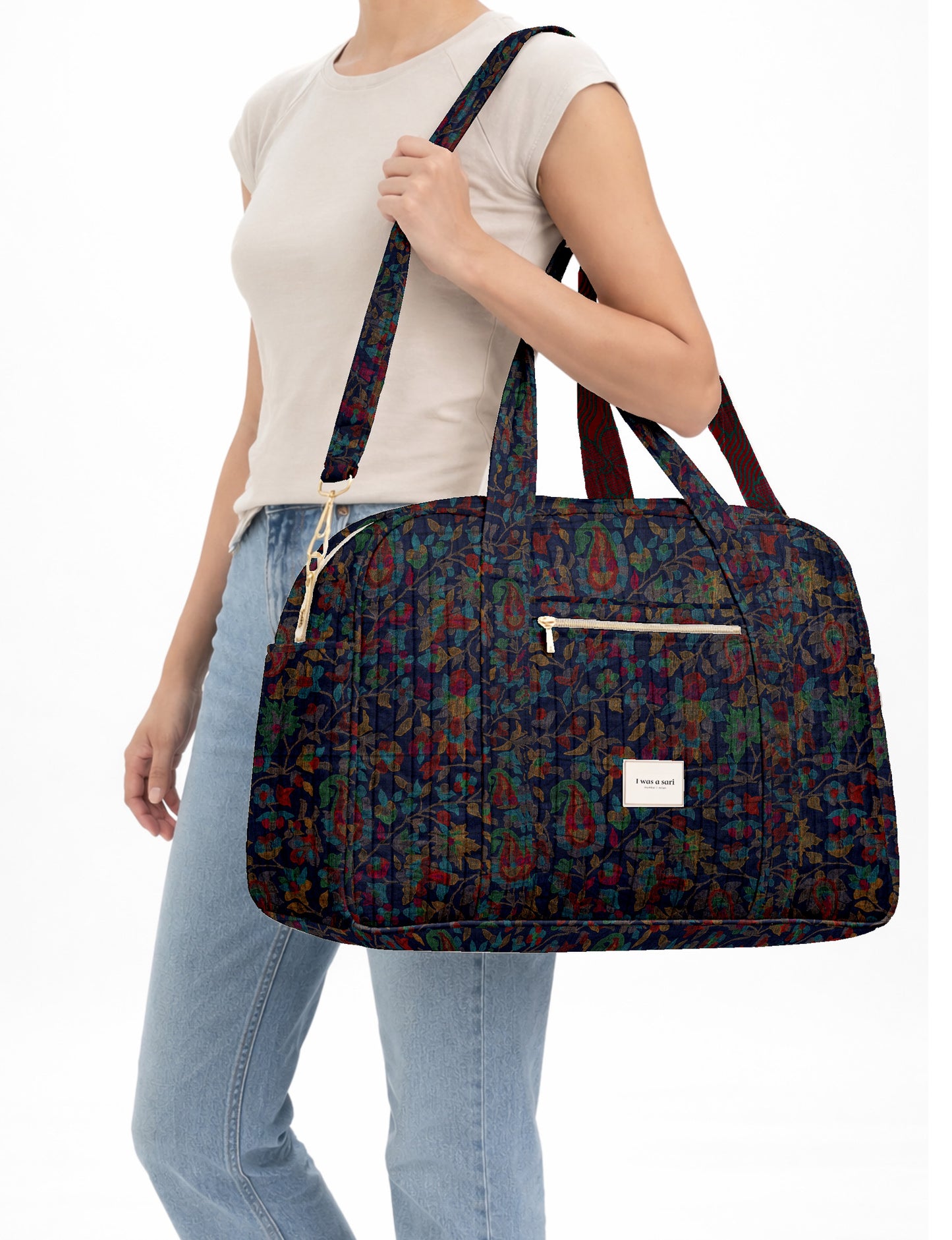 Brown quilted duffle bag with paisley pattern, front zip pocket, dual handles, and label reading "I was a sari"