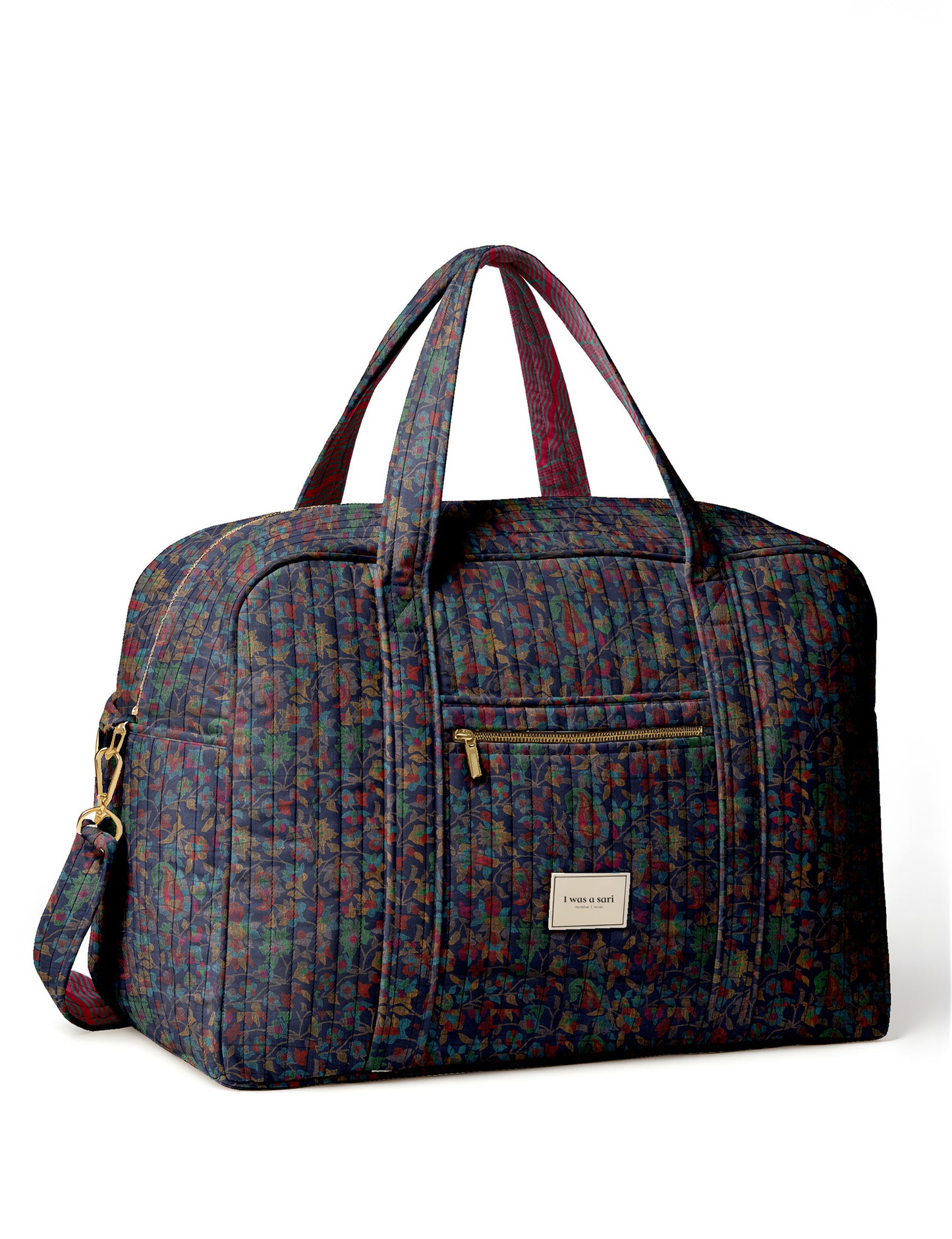 Brown quilted duffle bag with paisley pattern, front zip pocket, dual handles, and label reading "I was a sari"