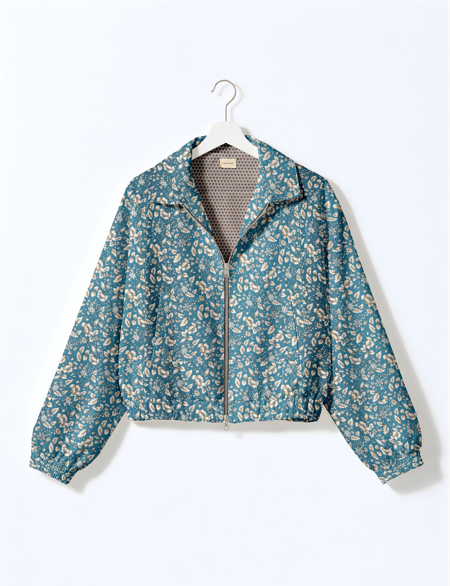 Women's cropped bomber jacket with twin metallic front zippers, welt pockets, elasticated hem and cuffs, and contrast sari print lining.