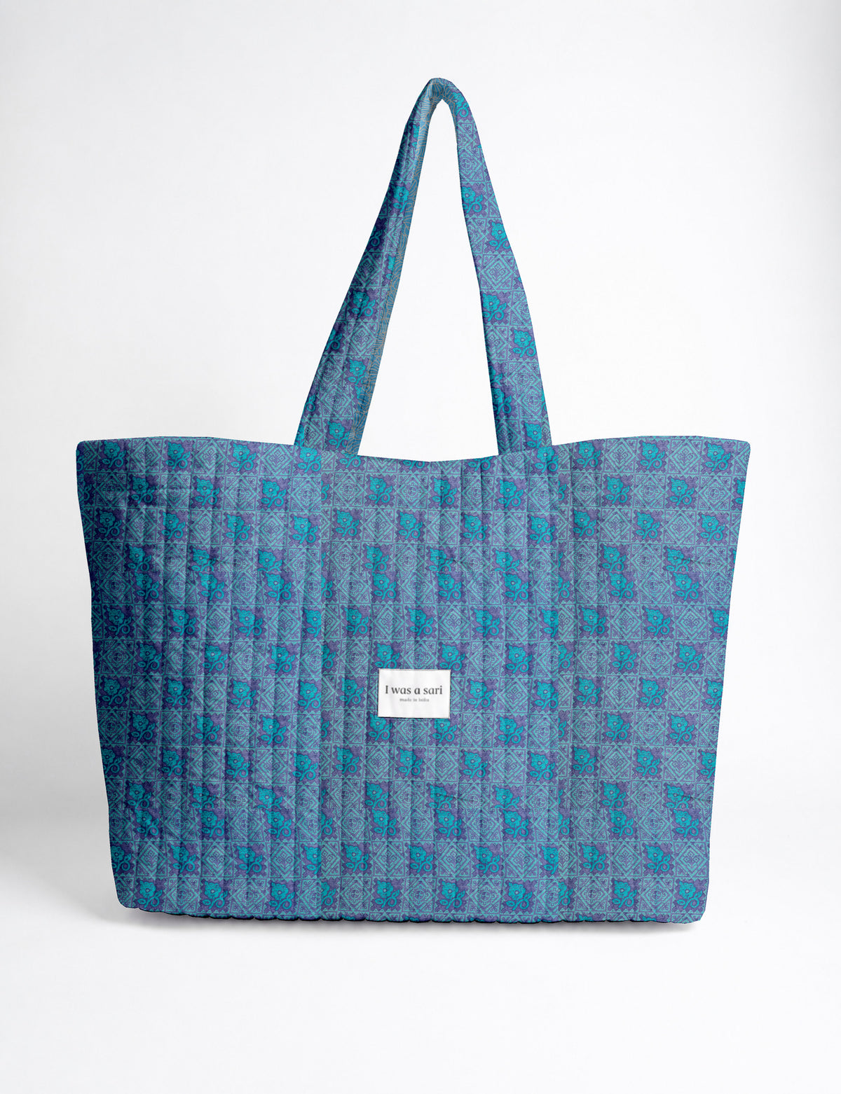 Quilted yellow tropical patterned beach bag with long handles and white label reading "I was a sari" front view