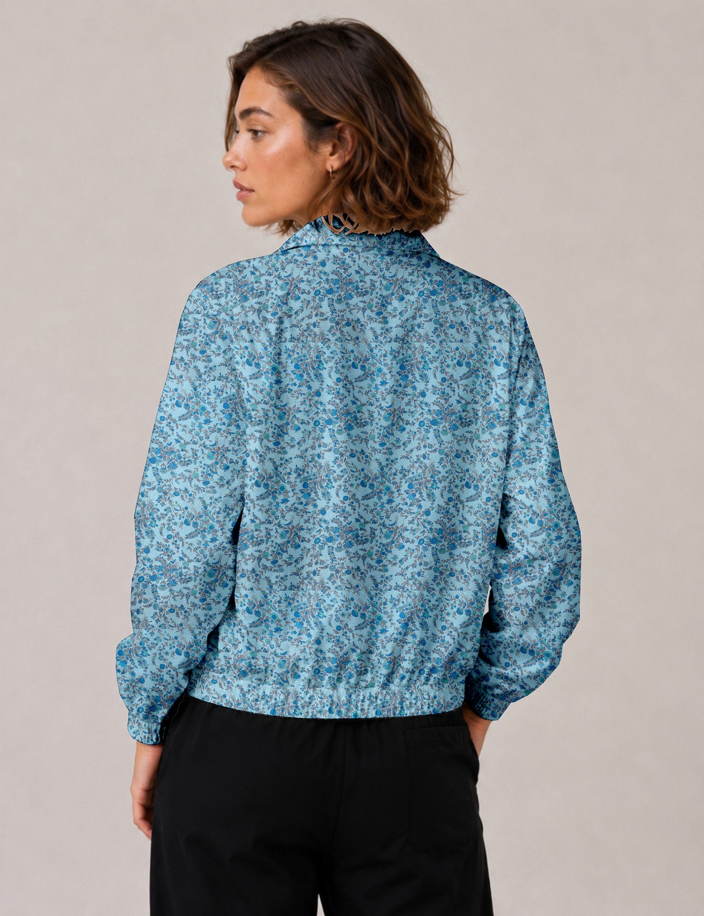 Woman wearing a yellow floral bomber jacket with front zipper, elastic cuffs, and side pockets, shown from front view