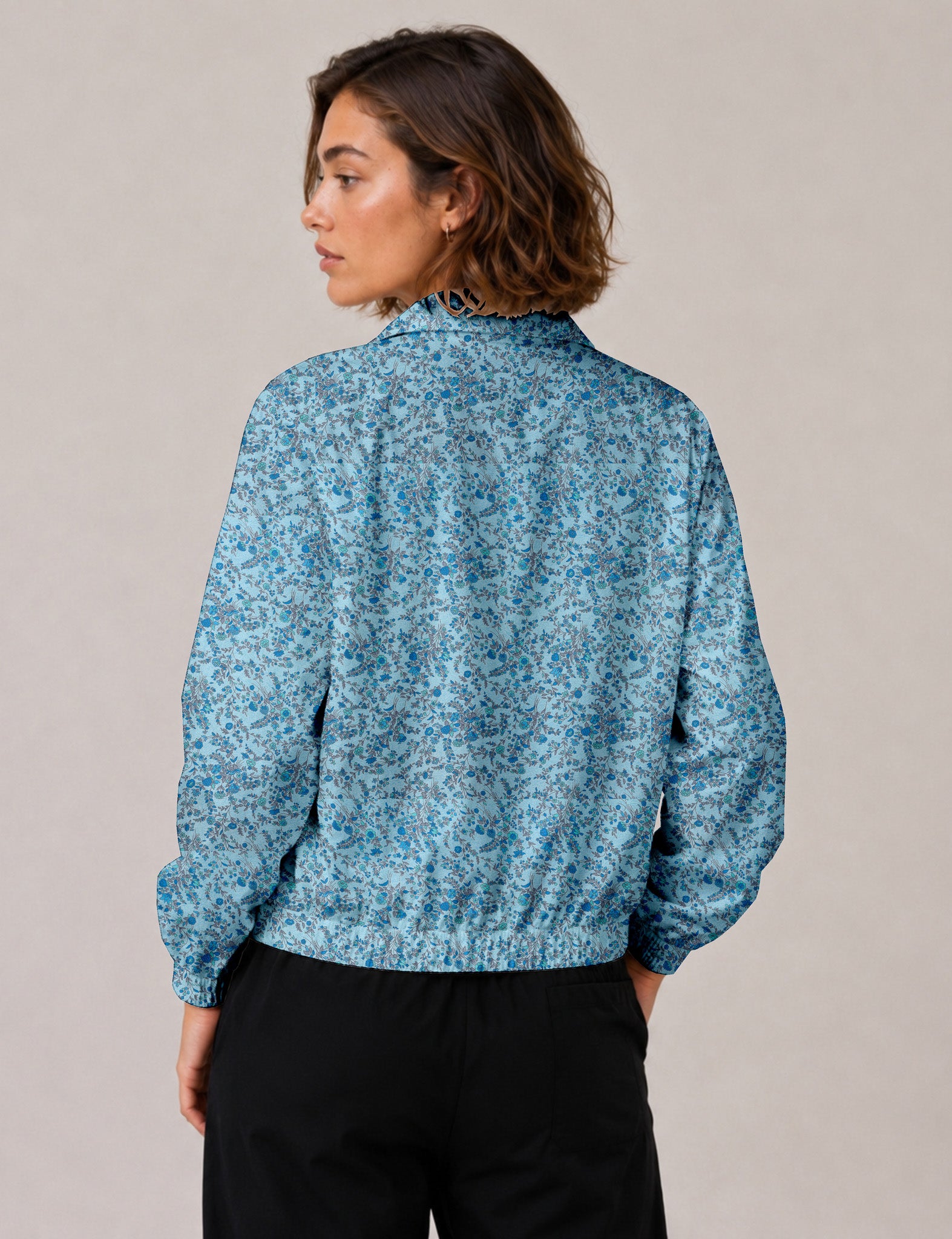 Woman wearing a yellow floral bomber jacket with front zipper, elastic cuffs, and side pockets, shown from front view