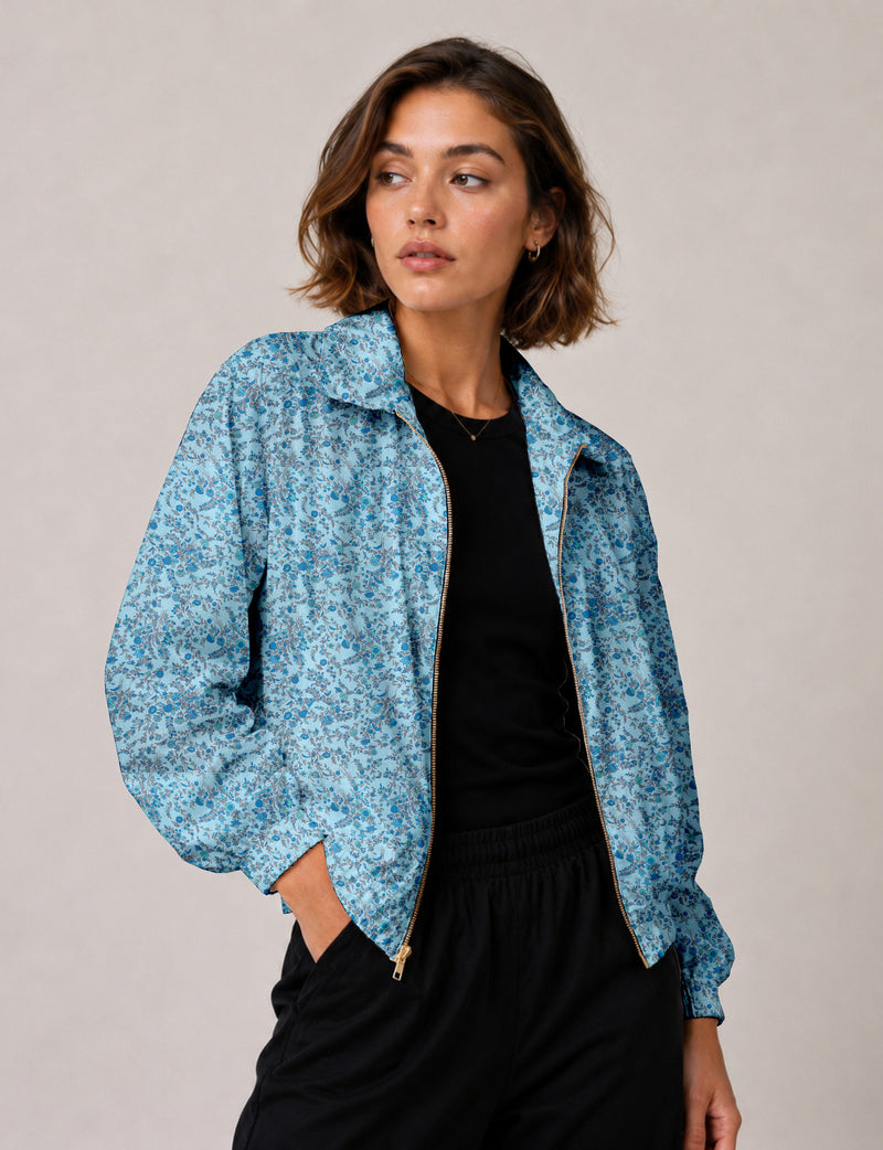 Woman wearing a yellow floral bomber jacket with front zipper, elastic cuffs, and side pockets, shown from front view