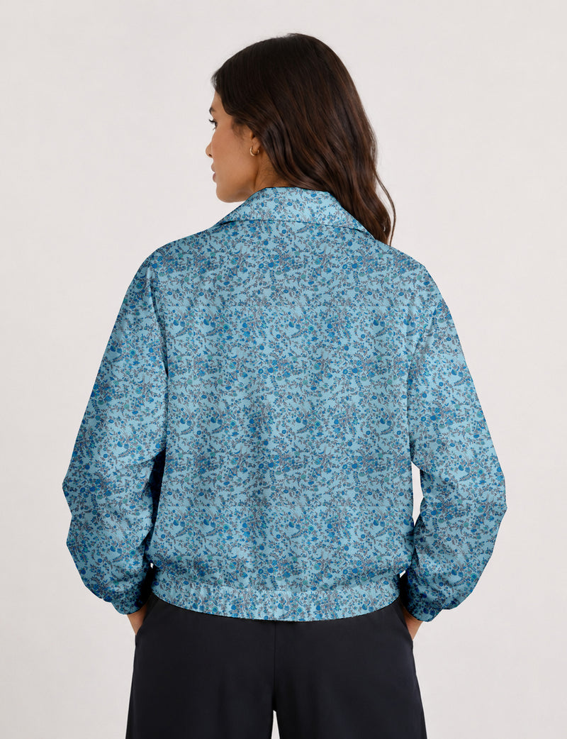 Woman wearing a yellow floral bomber jacket with front zipper, elastic cuffs, and side pockets, shown from front view