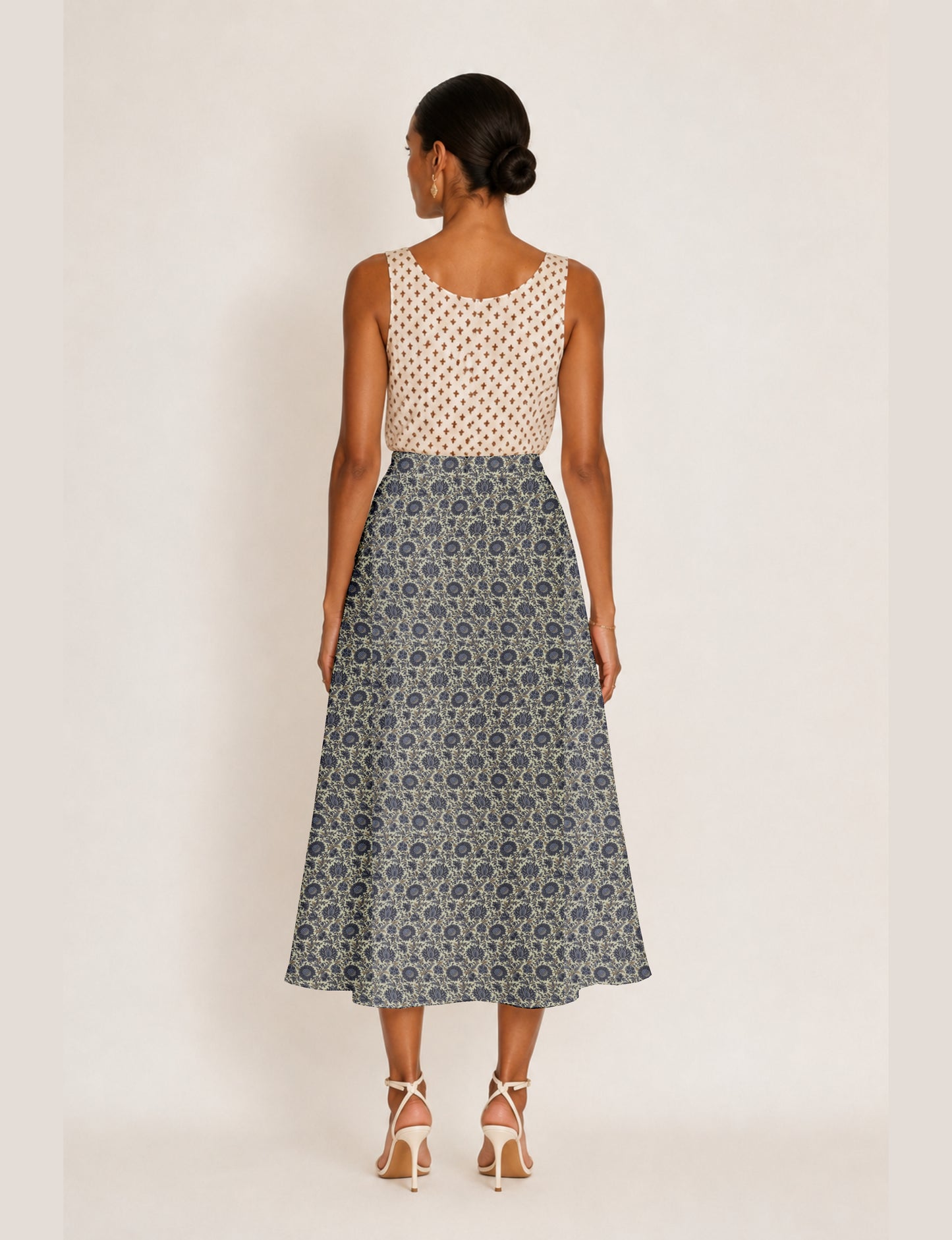 Woman wearing a yellow micro design A-line skirt with side slit, paired with a sleeveless beige top with small cross