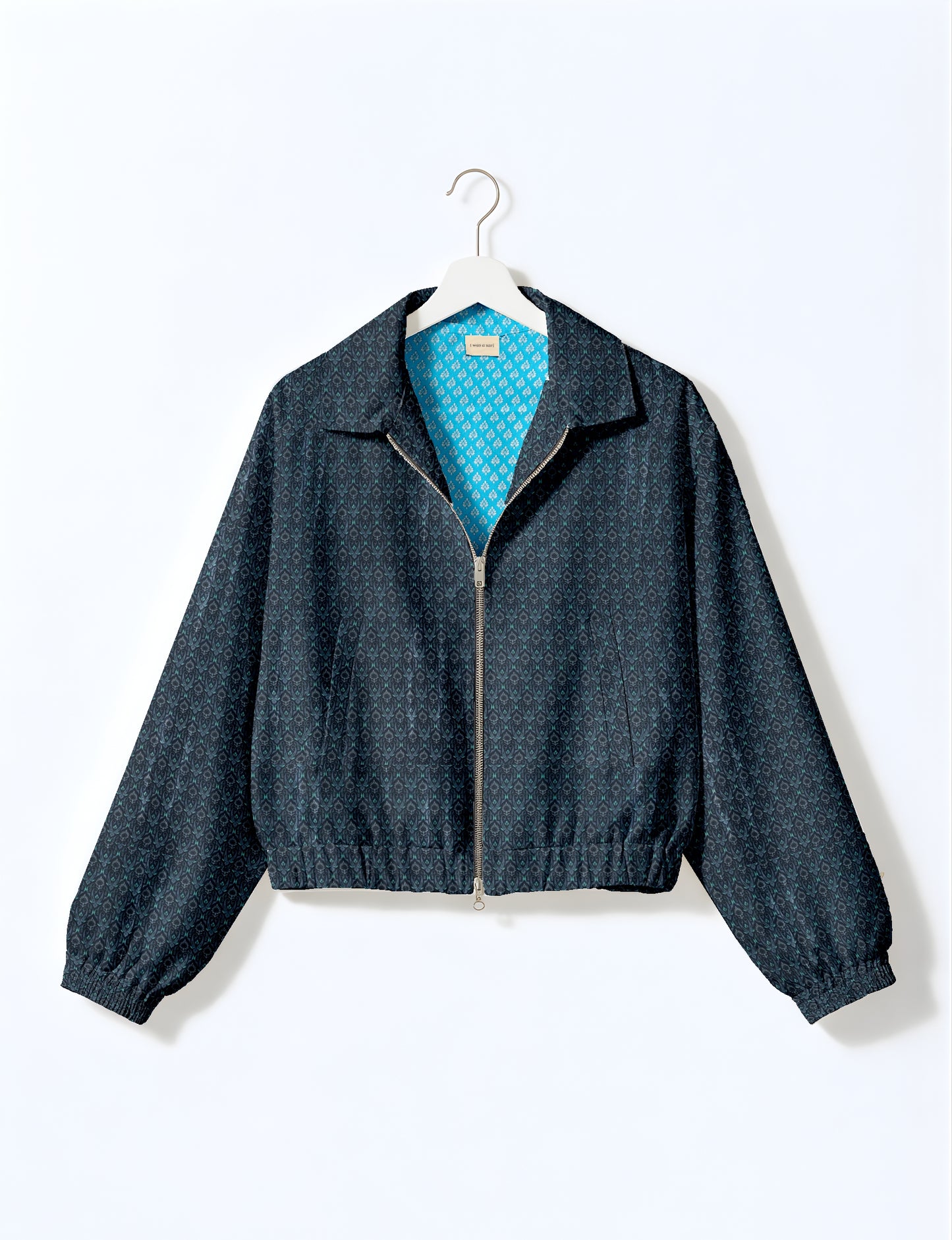Yellow bomber jacket with micro geometric pattern, silver front zipper, elastic cuffs, and blue floral inner lining, hanging