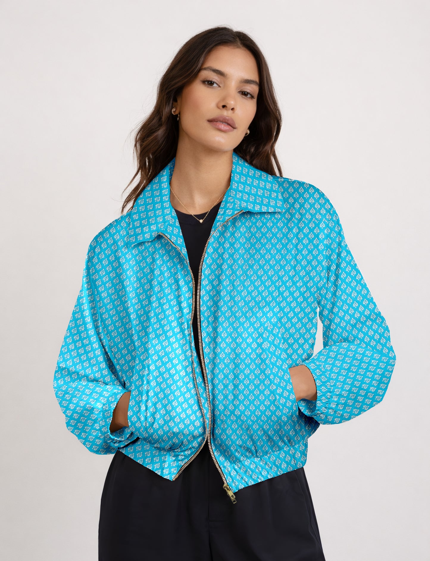 Woman wearing a yellow bomber jacket with a micro geometric pattern, front zipper, and side pockets, paired with black pants