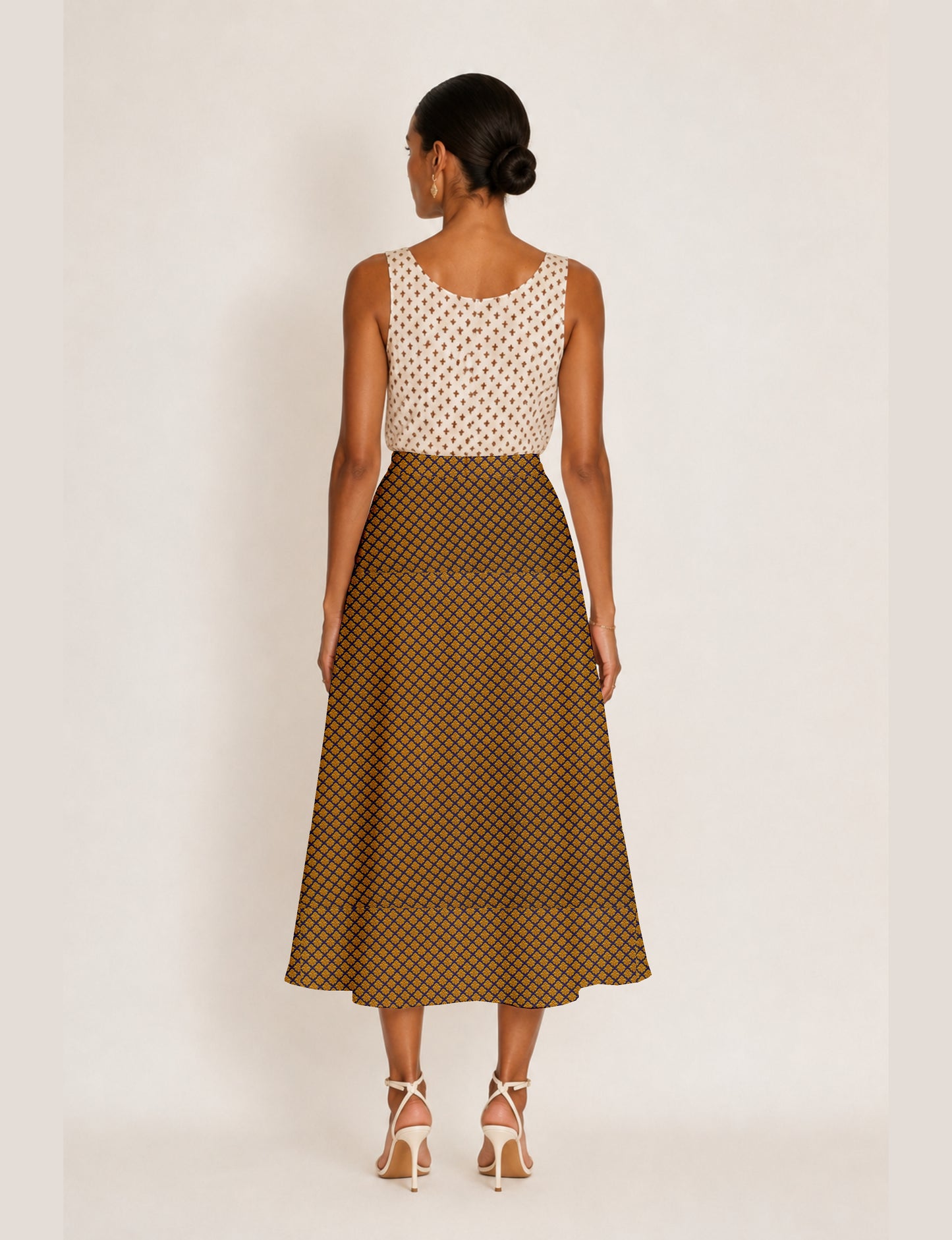 Woman wearing a yellow A-line skirt with a small geometric pattern, viewed from the back, paired with a sleeveless white top
