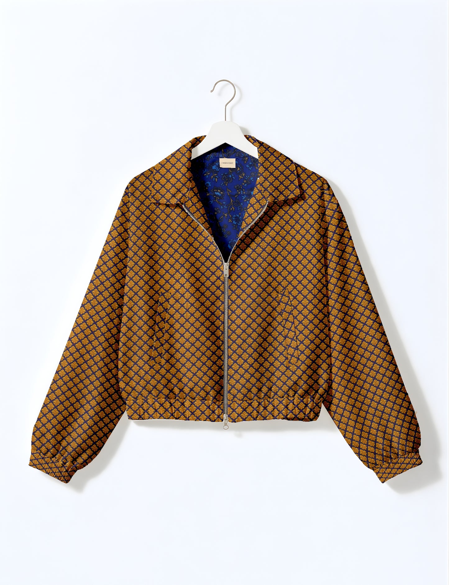 Yellow bomber jacket with micro geometric pattern, silver front zipper, elastic cuffs, and blue floral inner lining, hanging