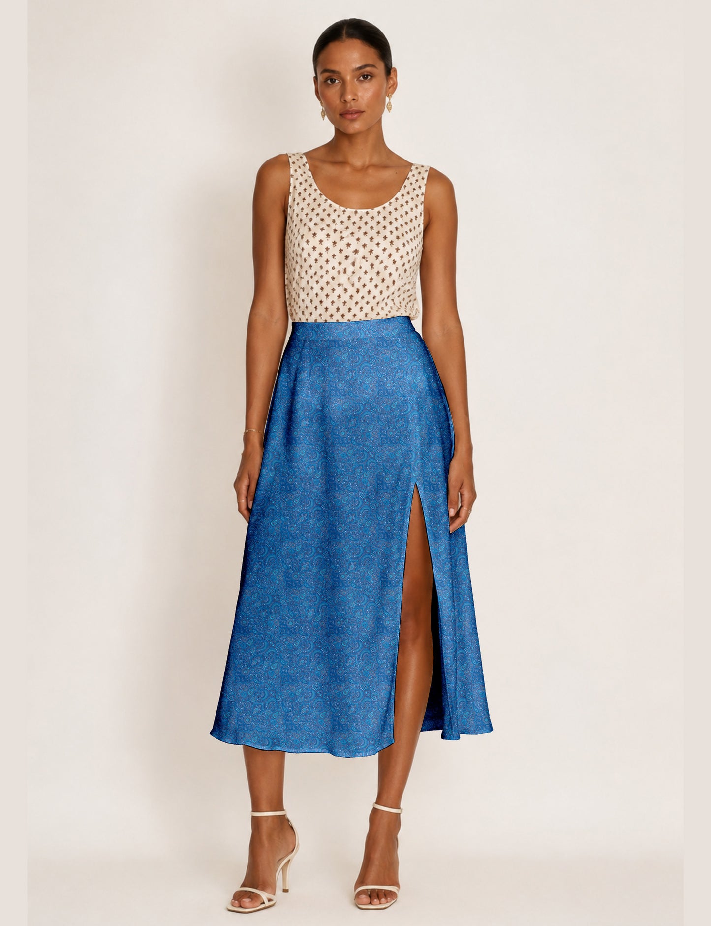 Woman wearing a yellow and black micro patterned A-line skirt with front slit, paired with beige sleeveless top and black