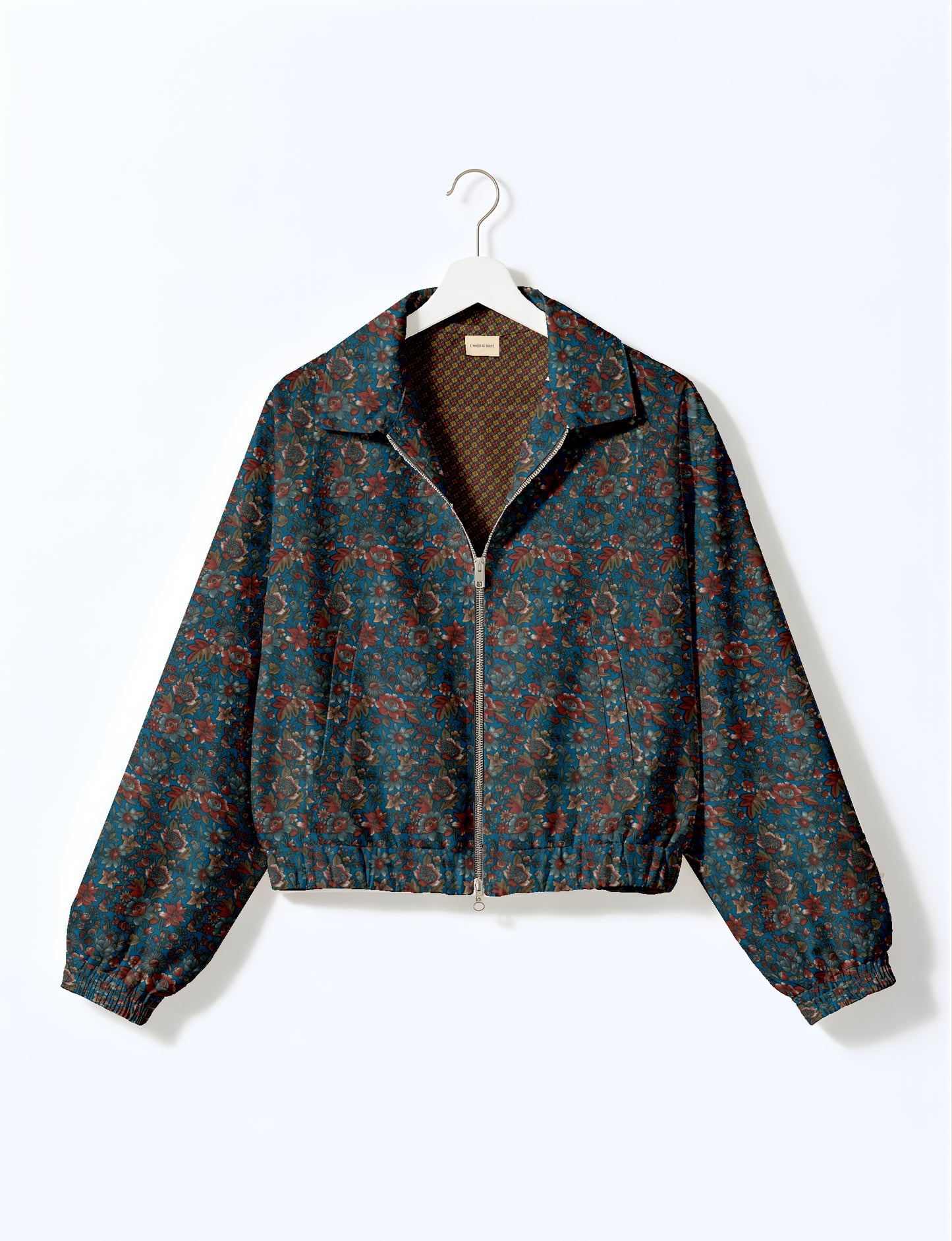 Women's cropped bomber jacket with twin metallic front zippers, welt pockets, elasticated hem and cuffs, and contrast sari print lining.