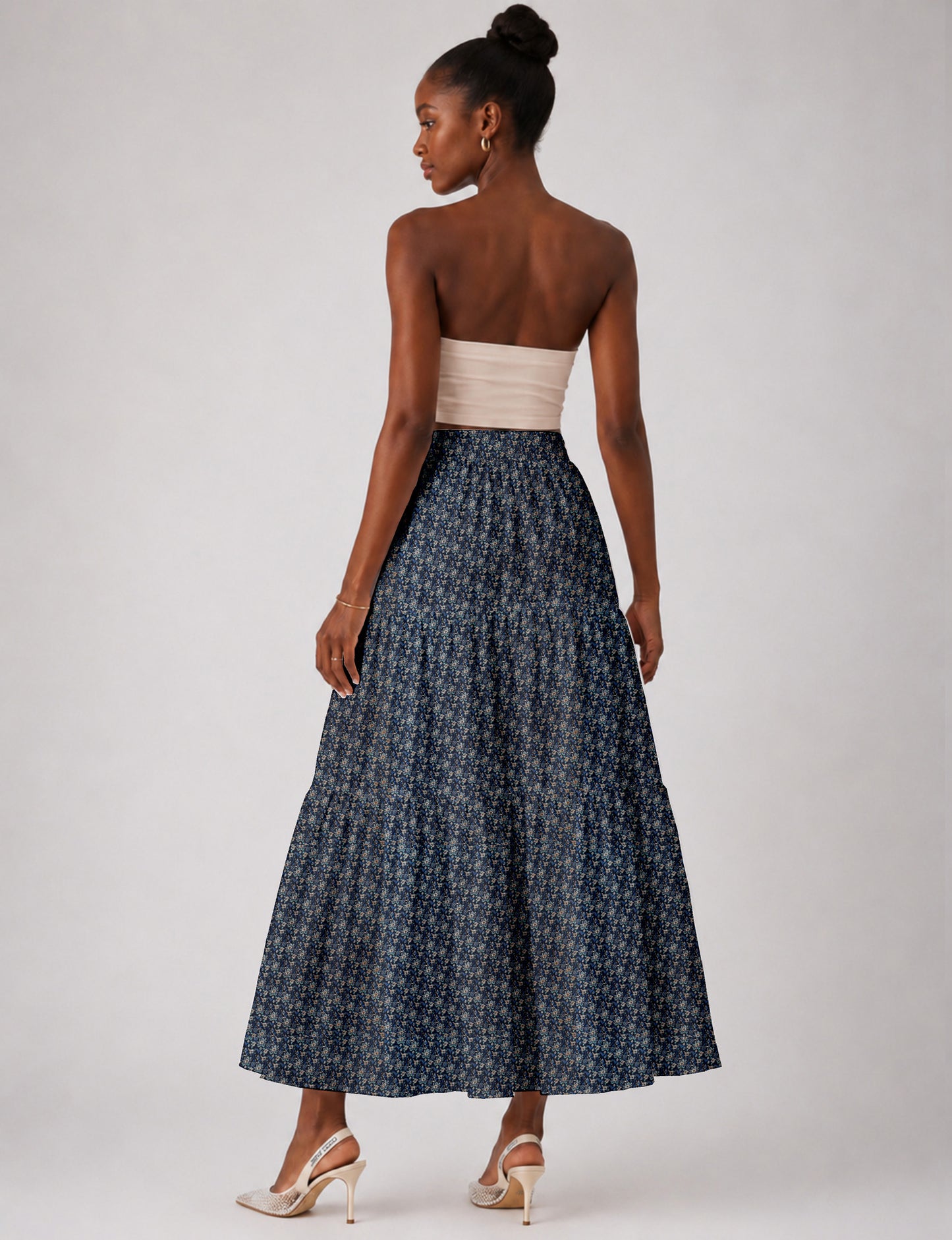 Woman wearing a yellow midi tiered skirt with a small geometric pattern, shown from the back, paired with beige top and