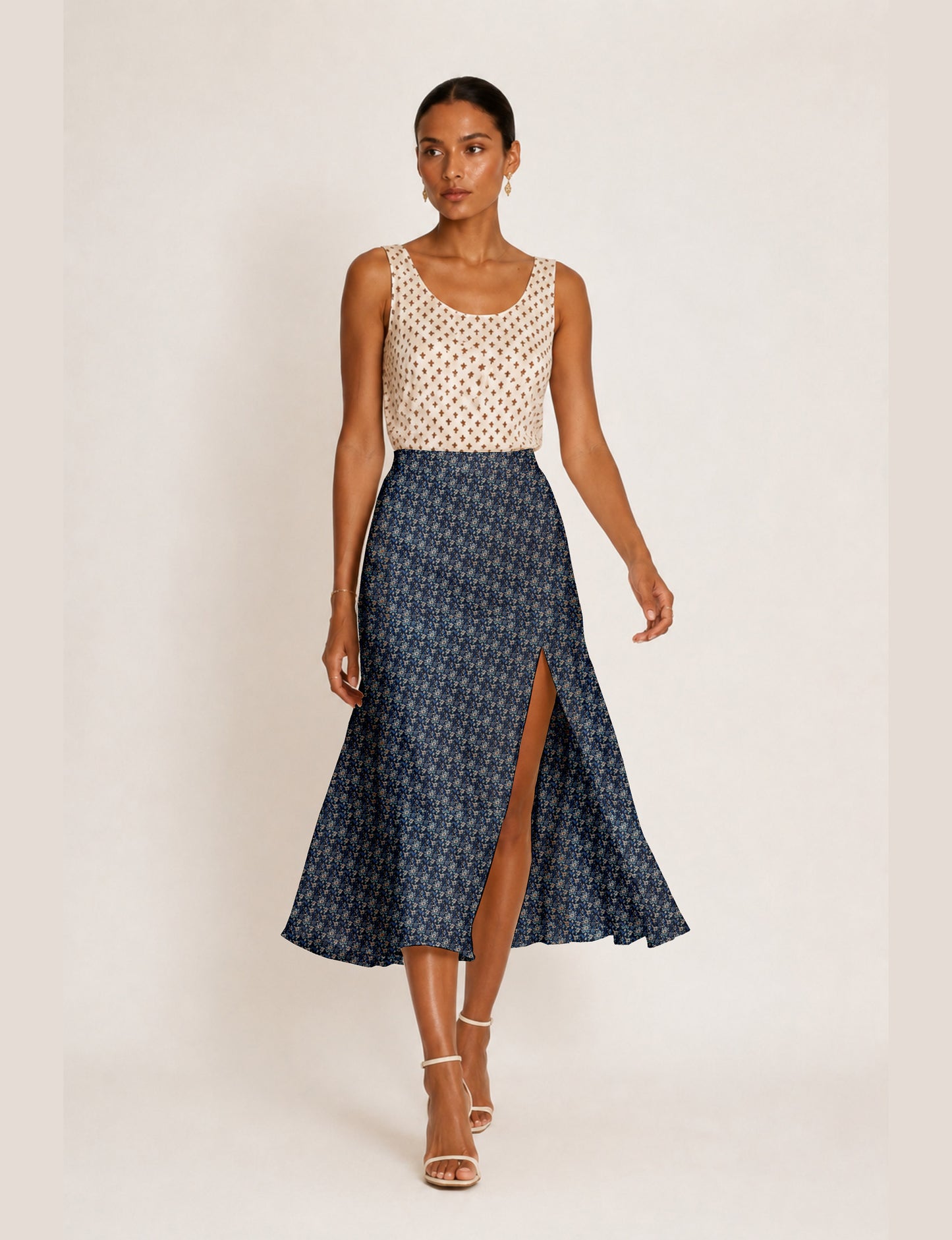 Woman wearing a yellow and black micro patterned A-line skirt with front slit, paired with beige sleeveless top and black