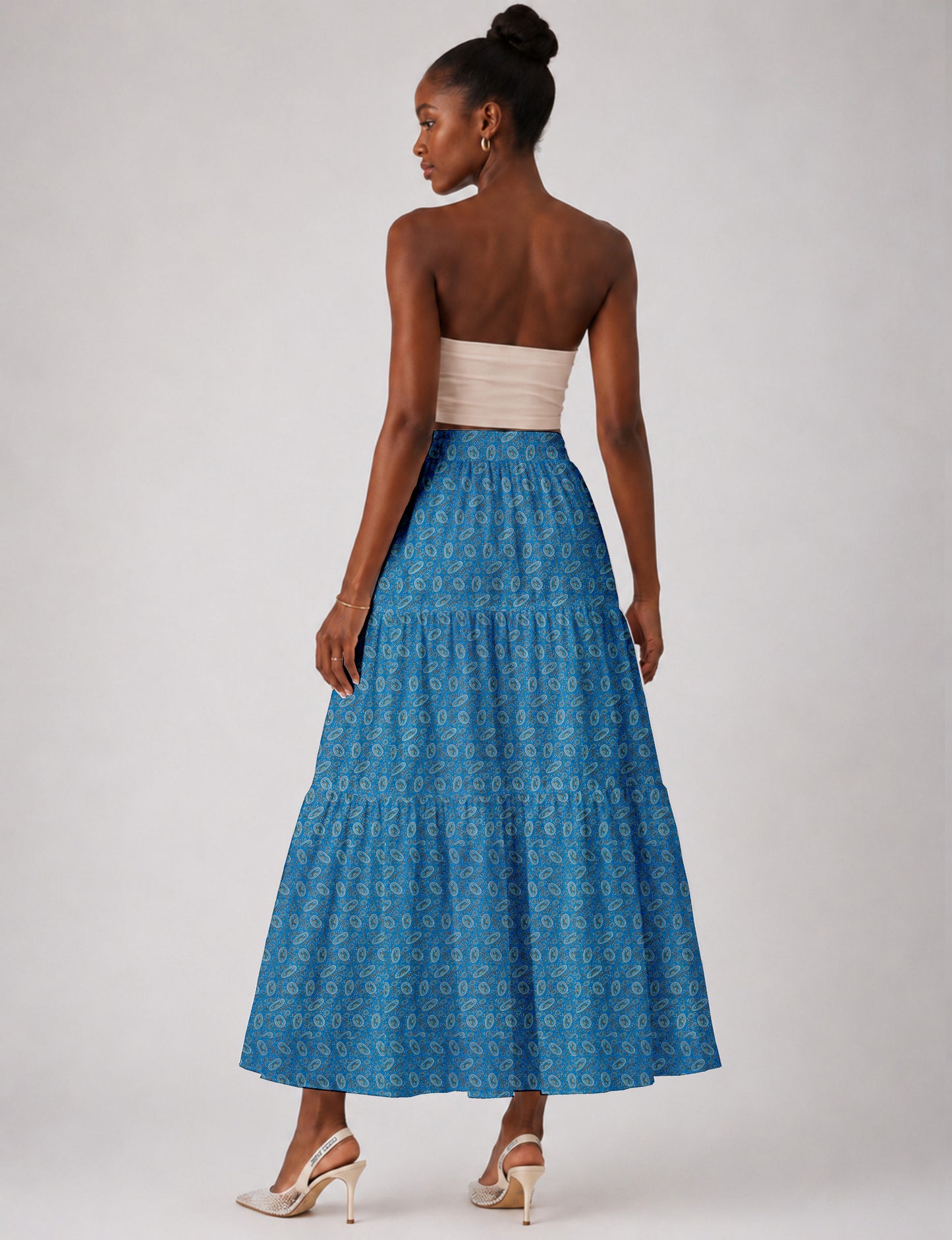Woman wearing a yellow midi tiered skirt with a small geometric pattern, shown from the back, paired with beige top and