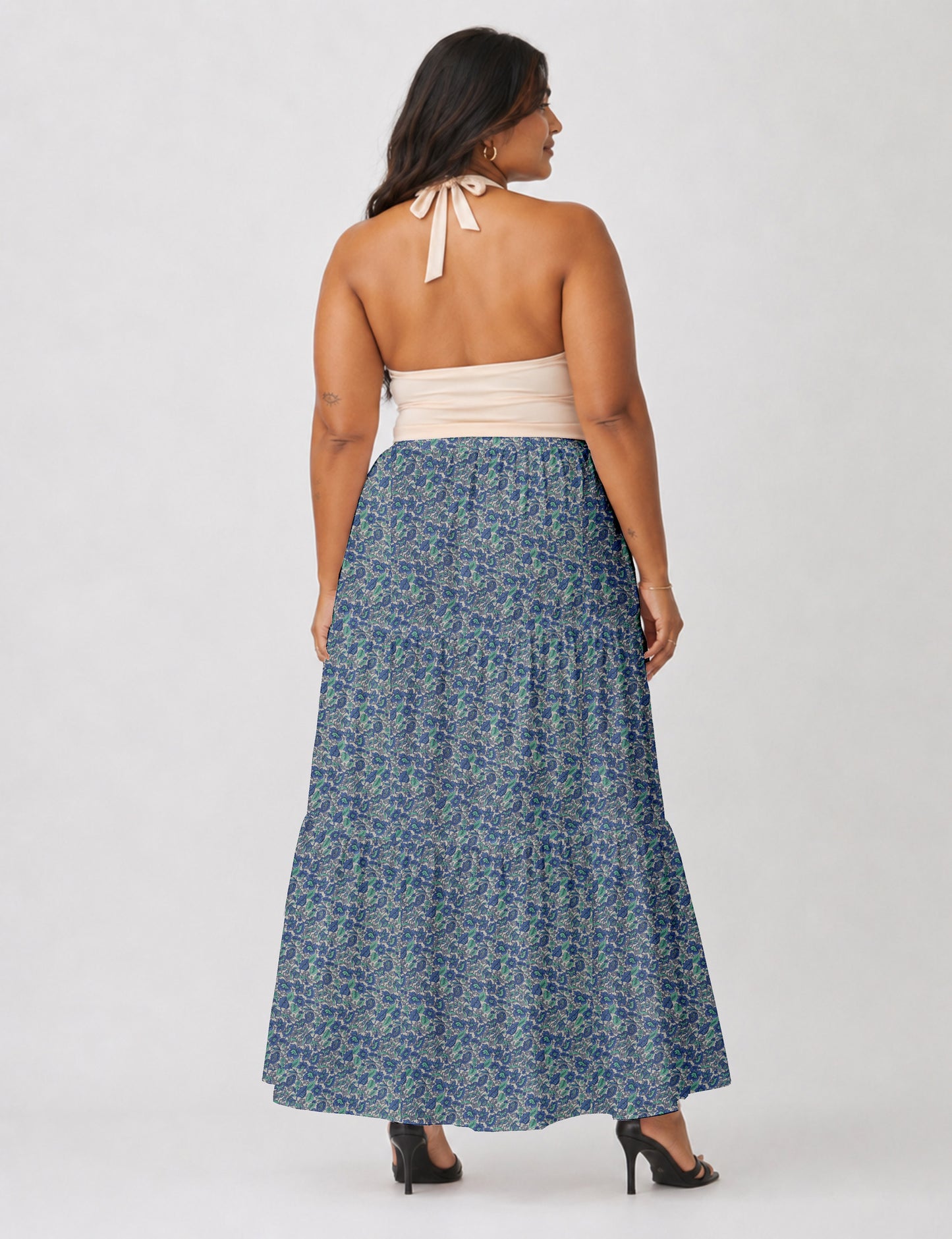 Woman wearing a yellow midi tiered skirt with a small geometric pattern, shown from the back, paired with beige top and