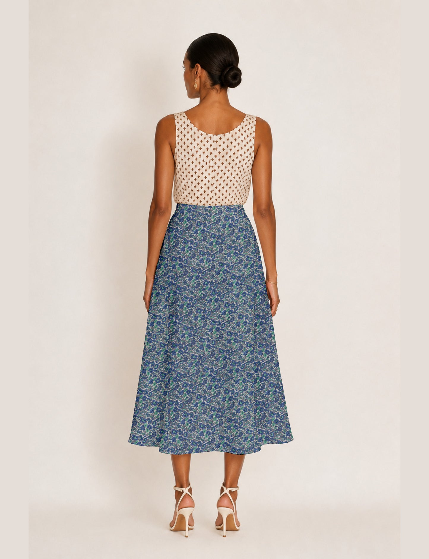 Woman wearing a yellow and black micro patterned A-line skirt with front slit, paired with beige sleeveless top and black