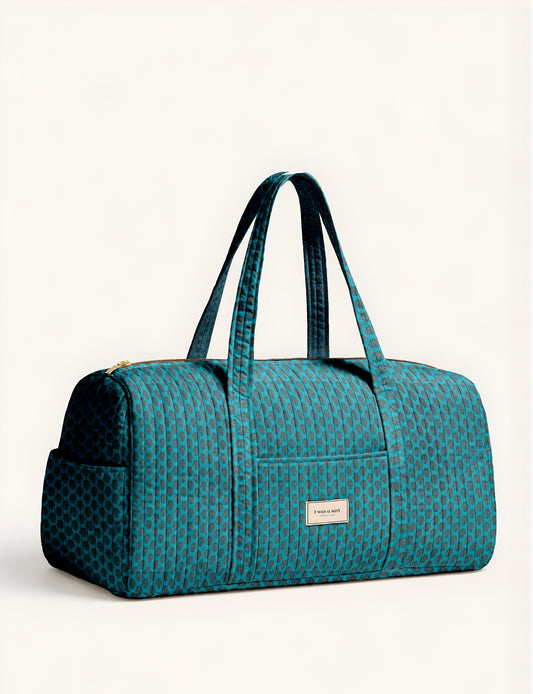 Quilted brown paisley barrel bag with double handles, front pocket, and gold zipper, shown in side angle view