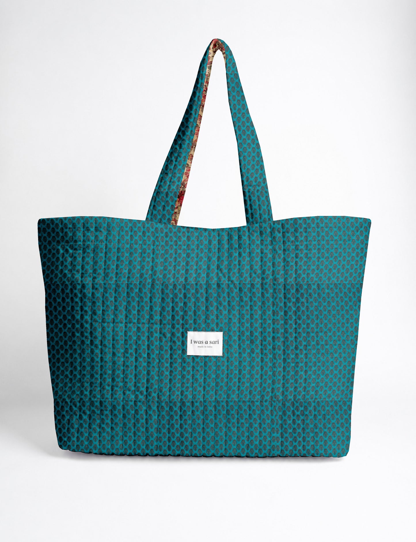 Quilted yellow tropical patterned beach bag with long handles and white label reading "I was a sari" front view