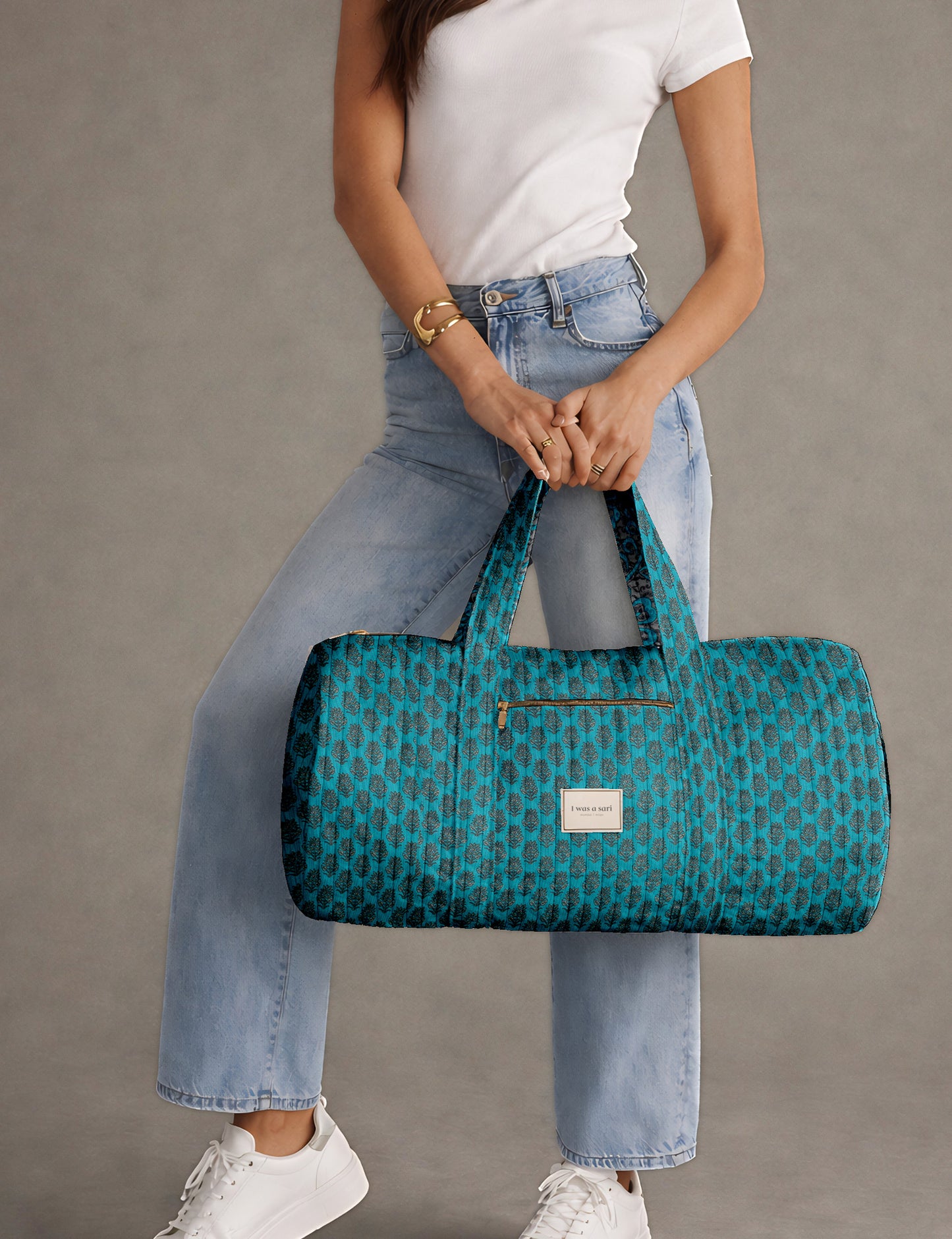 Brown paisley quilted bowling bag with front zipper pocket, held by person wearing white shirt and light blue jeans