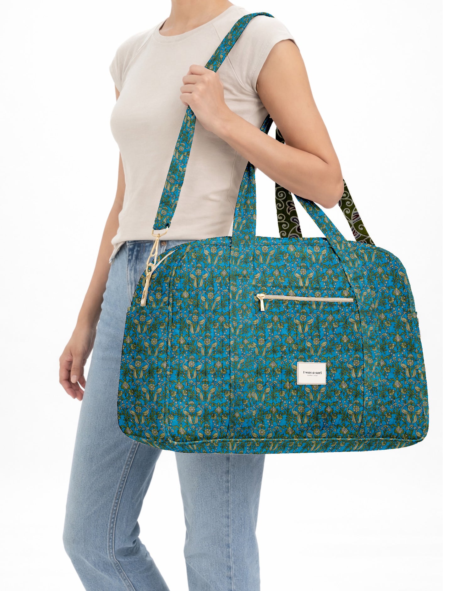 Brown quilted duffle bag with paisley pattern, front zip pocket, dual handles, and label reading "I was a sari"