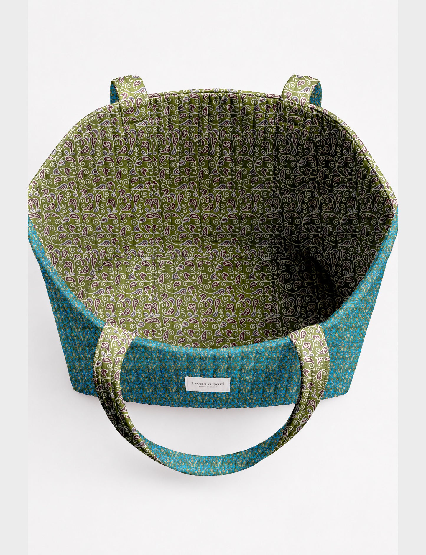 Quilted beach bag with yellow tropical exterior and red patterned interior, shown from top view with handles visible