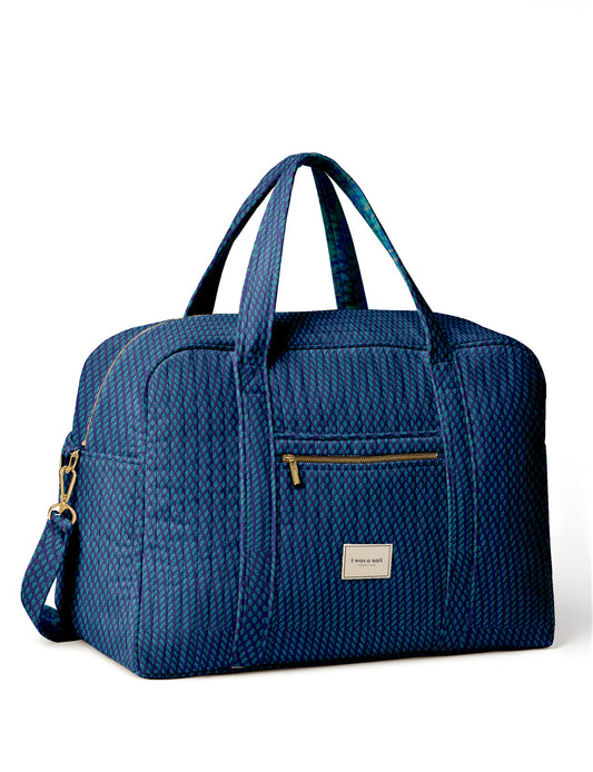 Brown quilted duffle bag with paisley pattern, front zip pocket, dual handles, and label reading "I was a sari"