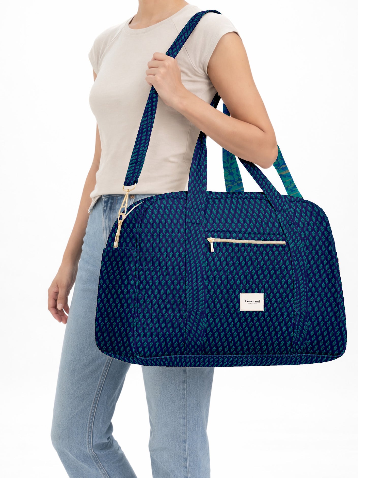 Brown quilted duffle bag with paisley pattern, front zip pocket, dual handles, and label reading "I was a sari"