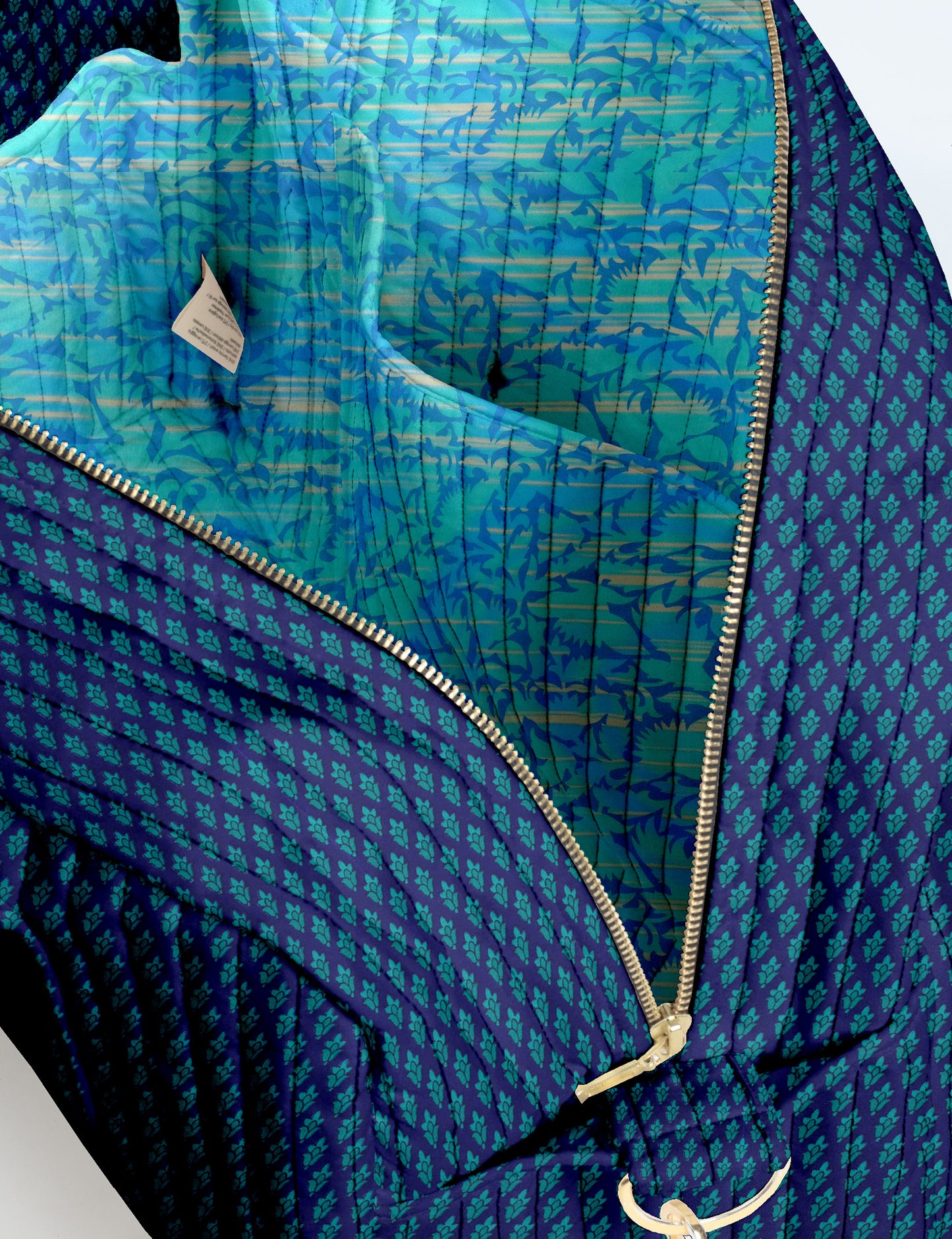 Brown quilted duffle bag with paisley pattern, front zip pocket, dual handles, and label reading "I was a sari"