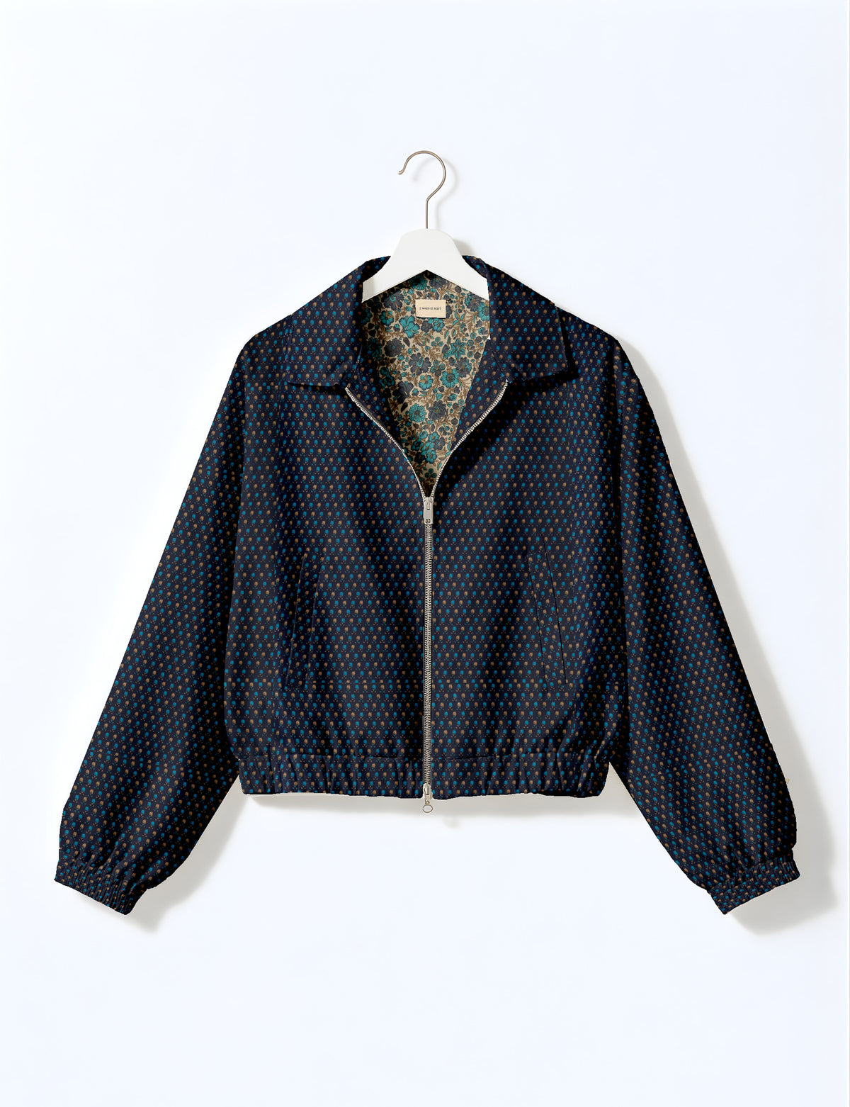 Brown floral bomber jacket with front zipper, elastic cuffs and hem, hanging on white hanger, red floral inner lining visible