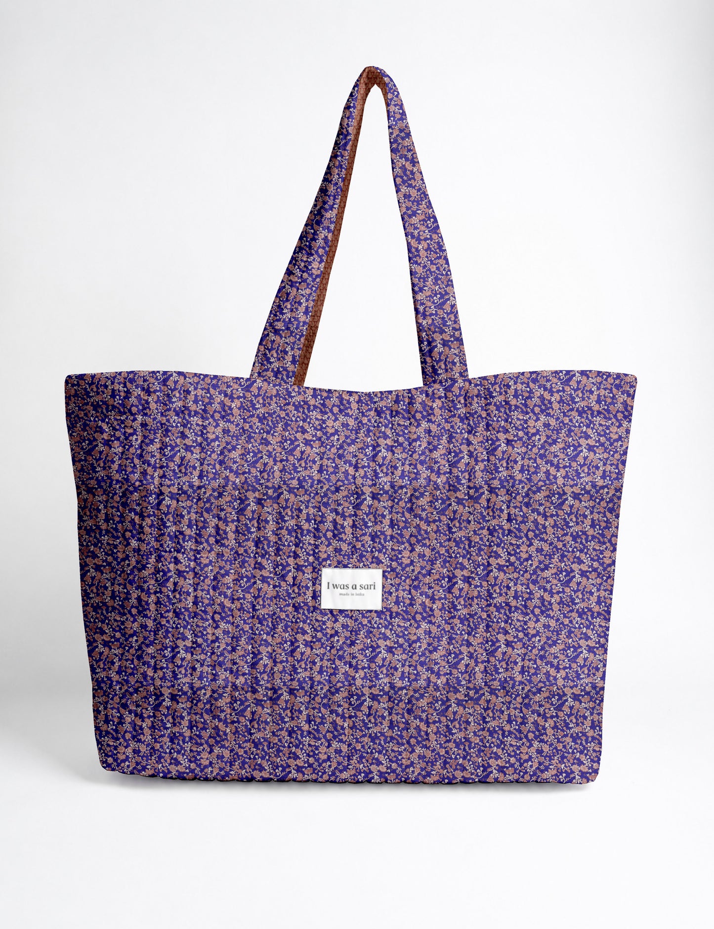 Quilted yellow tropical patterned beach bag with long handles and white label reading "I was a sari" front view