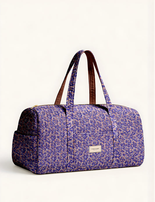 Quilted brown paisley barrel bag with double handles, front pocket, and gold zipper, shown in side angle view