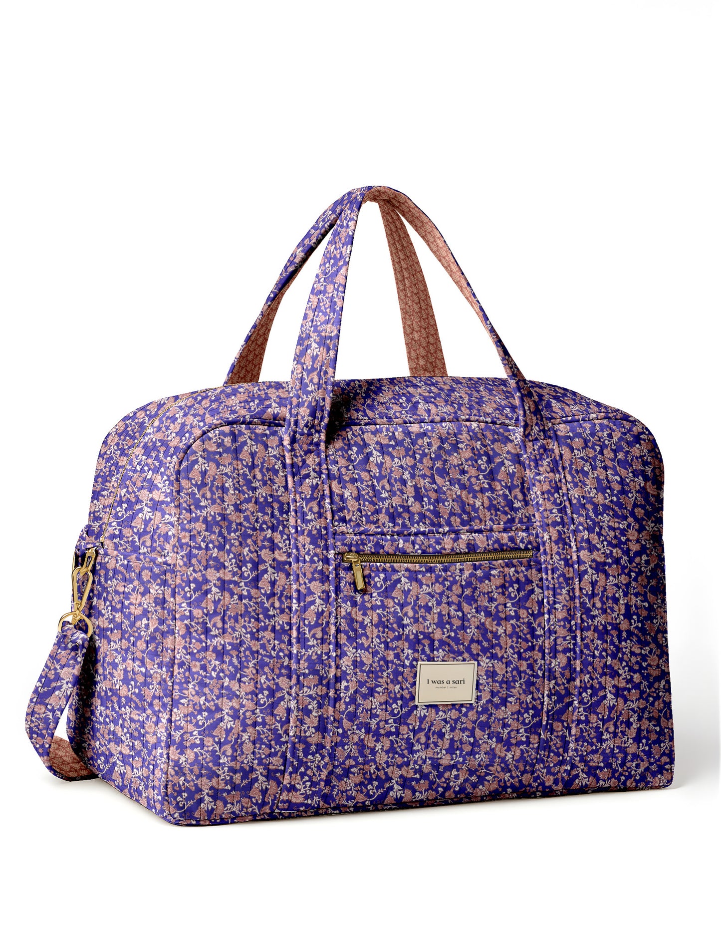 Brown quilted duffle bag with paisley pattern, front zip pocket, dual handles, and label reading "I was a sari"