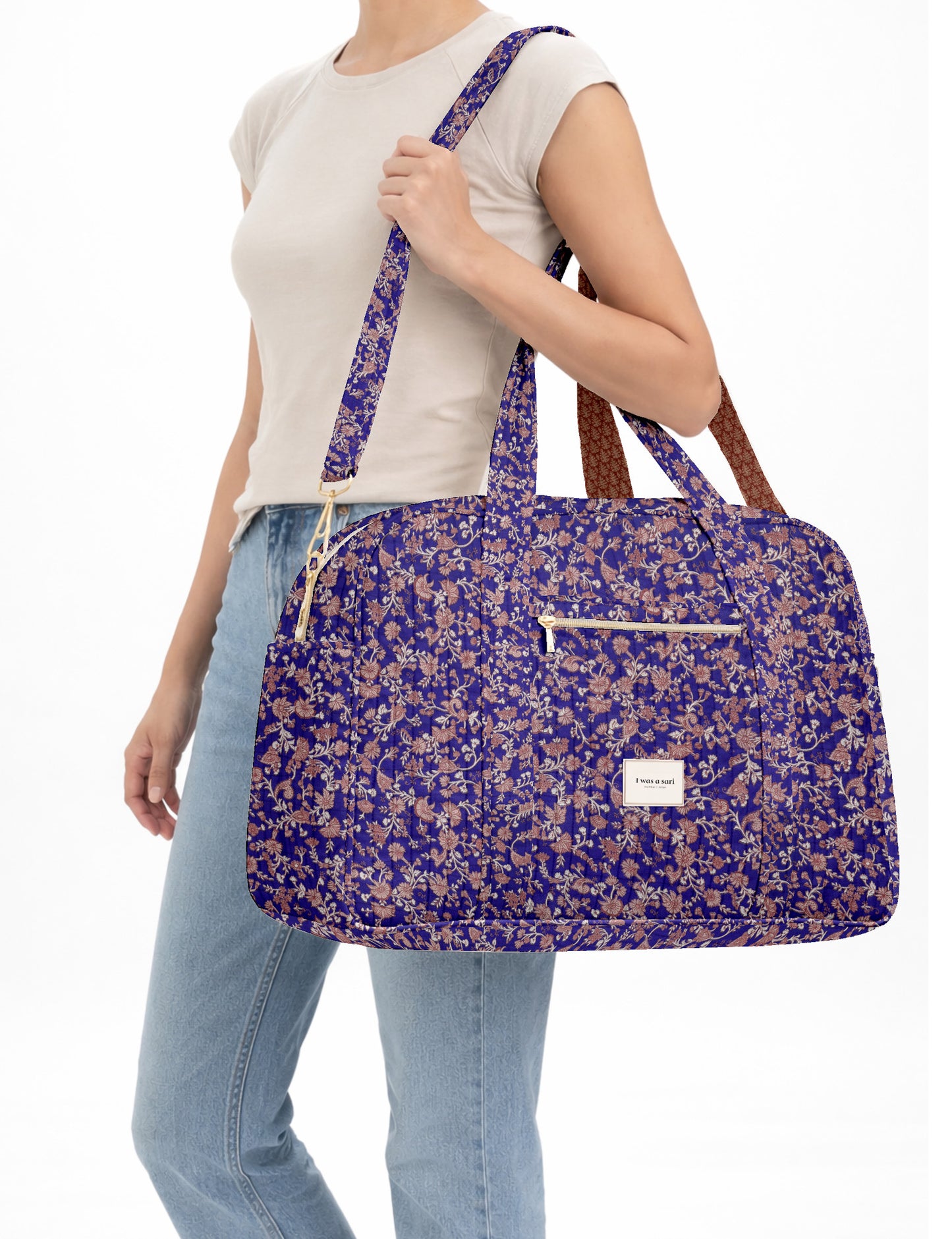 Brown quilted duffle bag with paisley pattern, front zip pocket, dual handles, and label reading "I was a sari"