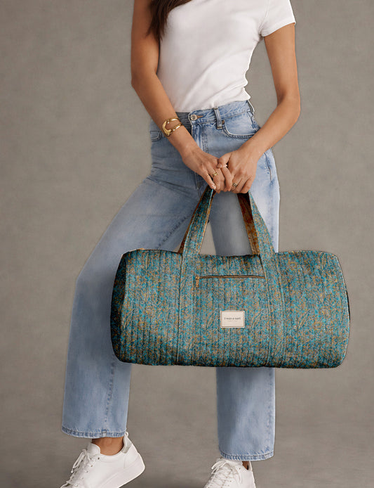 Brown paisley quilted bowling bag with dual handles, front zipper pocket, and "I was a sari" label on front side