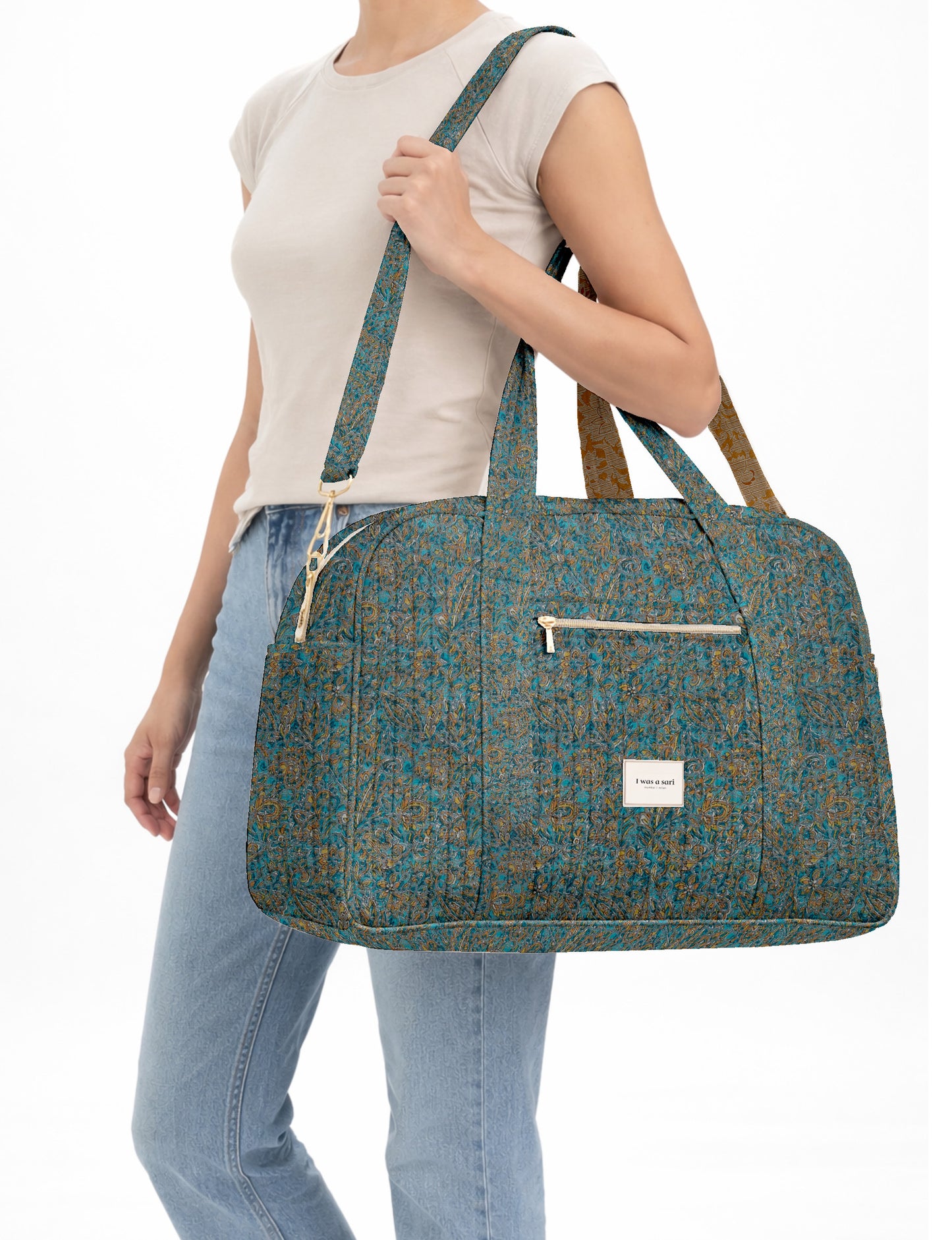 Brown quilted duffle bag with paisley pattern, front zip pocket, dual handles, and label reading "I was a sari"