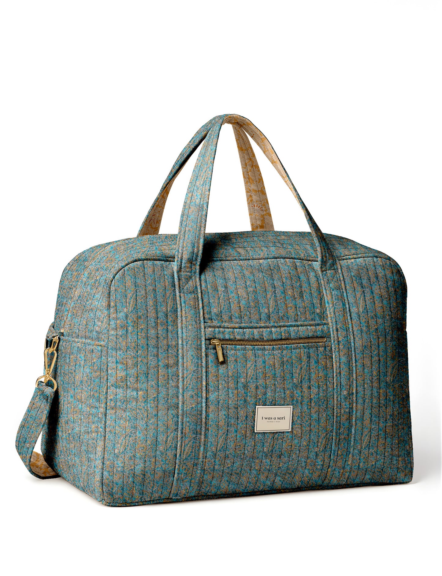 Brown quilted duffle bag with paisley pattern, front zip pocket, dual handles, and label reading "I was a sari"