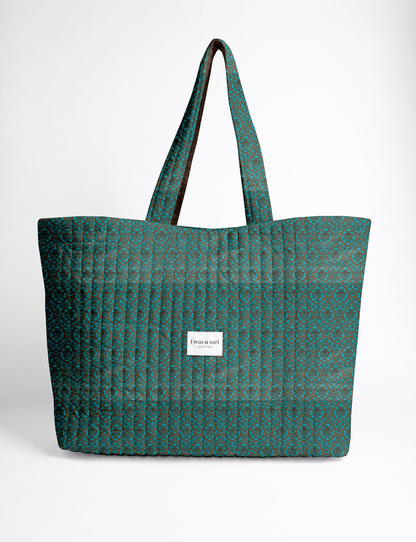 Quilted yellow tropical patterned beach bag with long handles and white label reading "I was a sari" front view