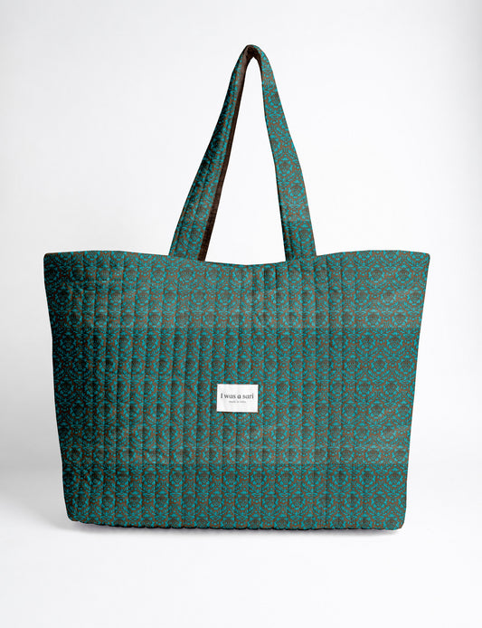 Quilted yellow tropical patterned beach bag with long handles and white label reading "I was a sari" front view