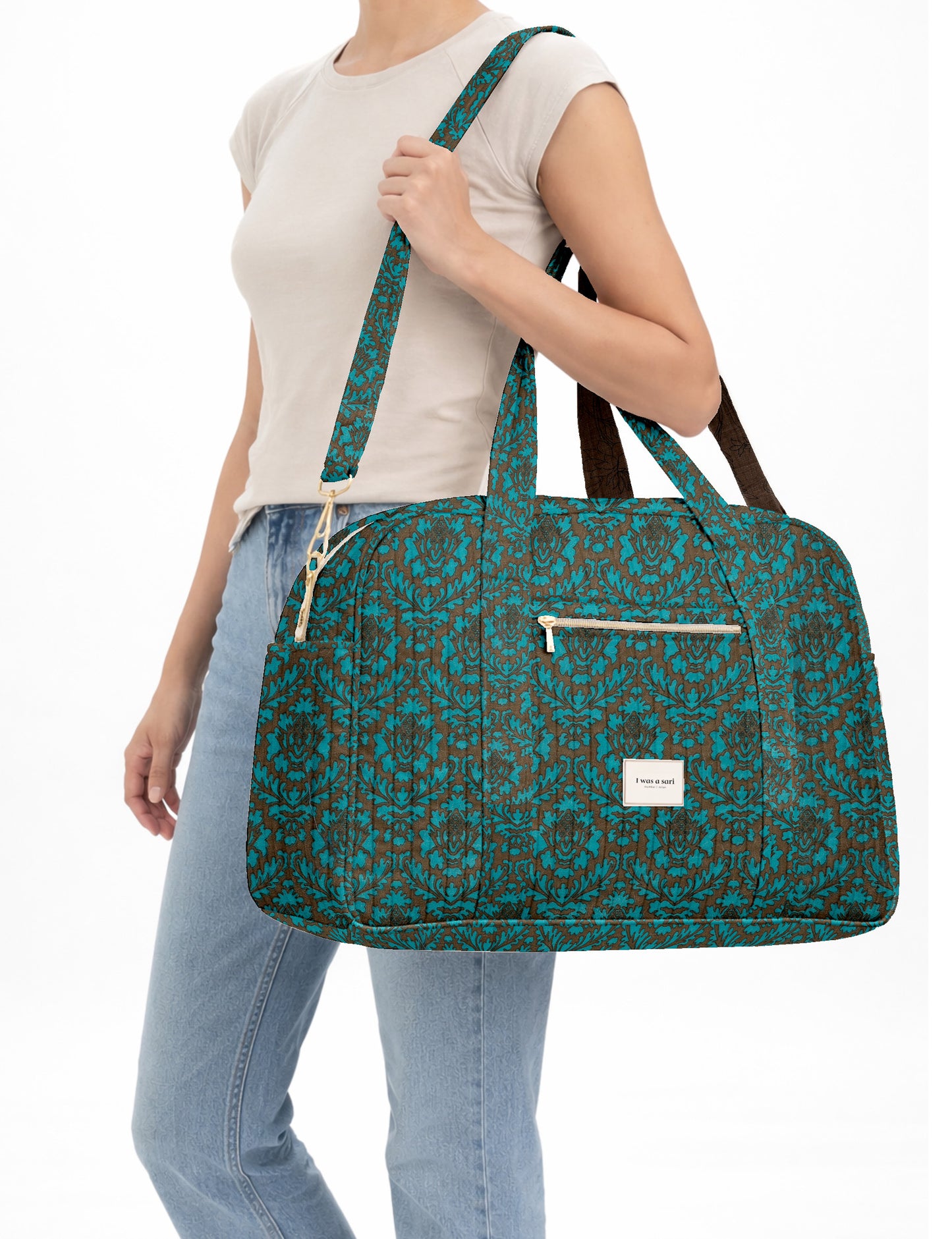 Brown quilted duffle bag with paisley pattern, front zip pocket, dual handles, and label reading "I was a sari"