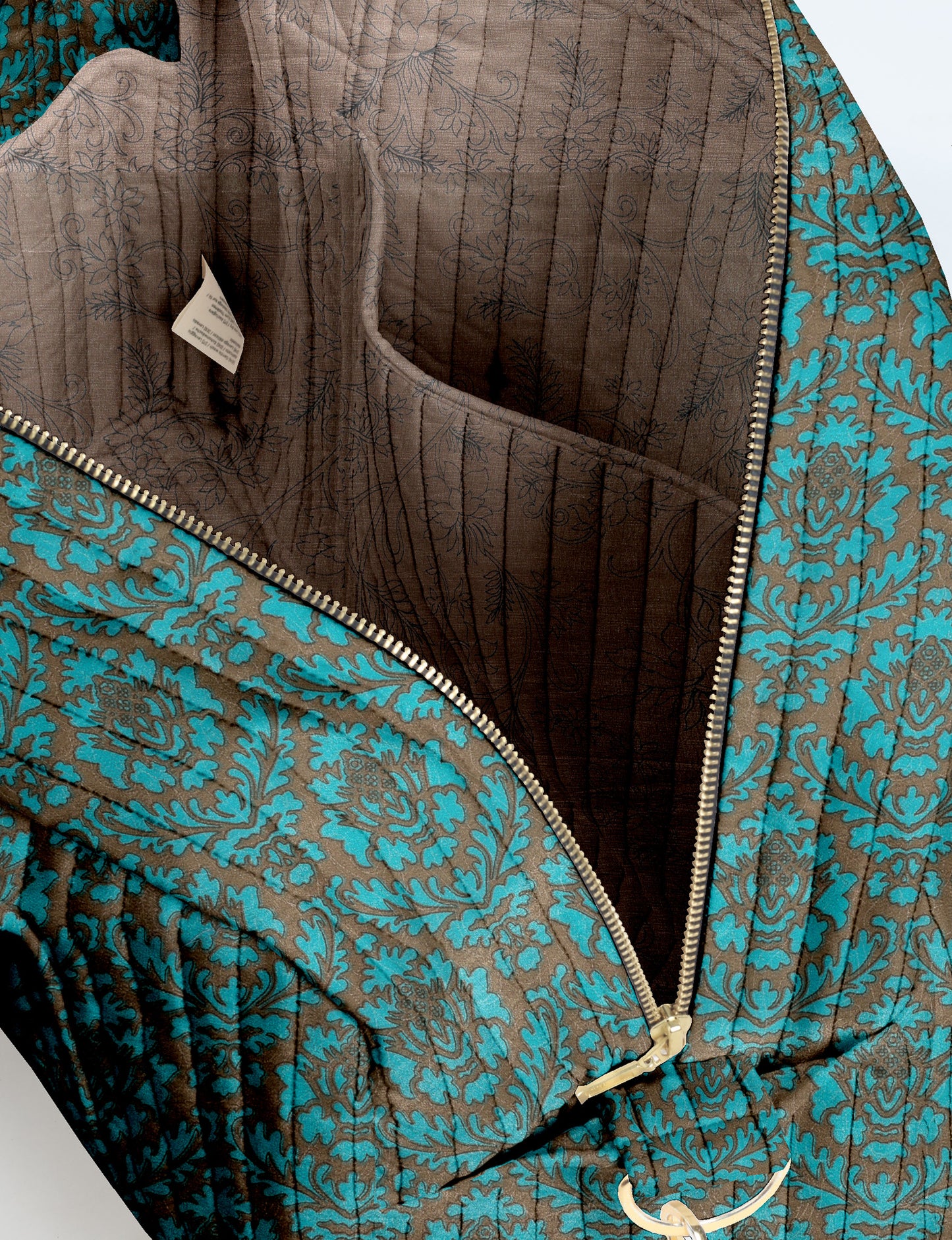 Brown quilted duffle bag with paisley pattern, front zip pocket, dual handles, and label reading "I was a sari"