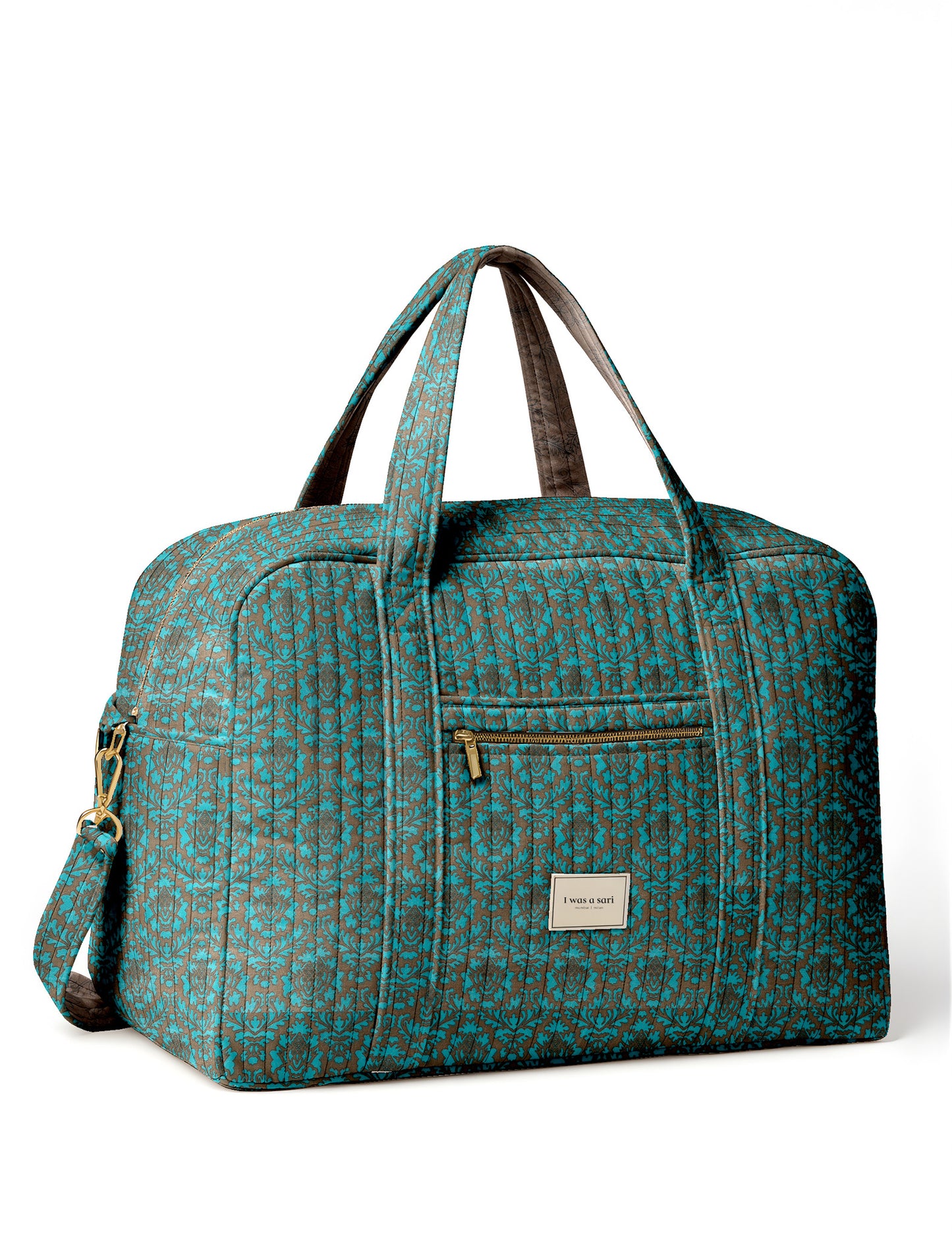 Brown quilted duffle bag with paisley pattern, front zip pocket, dual handles, and label reading "I was a sari"