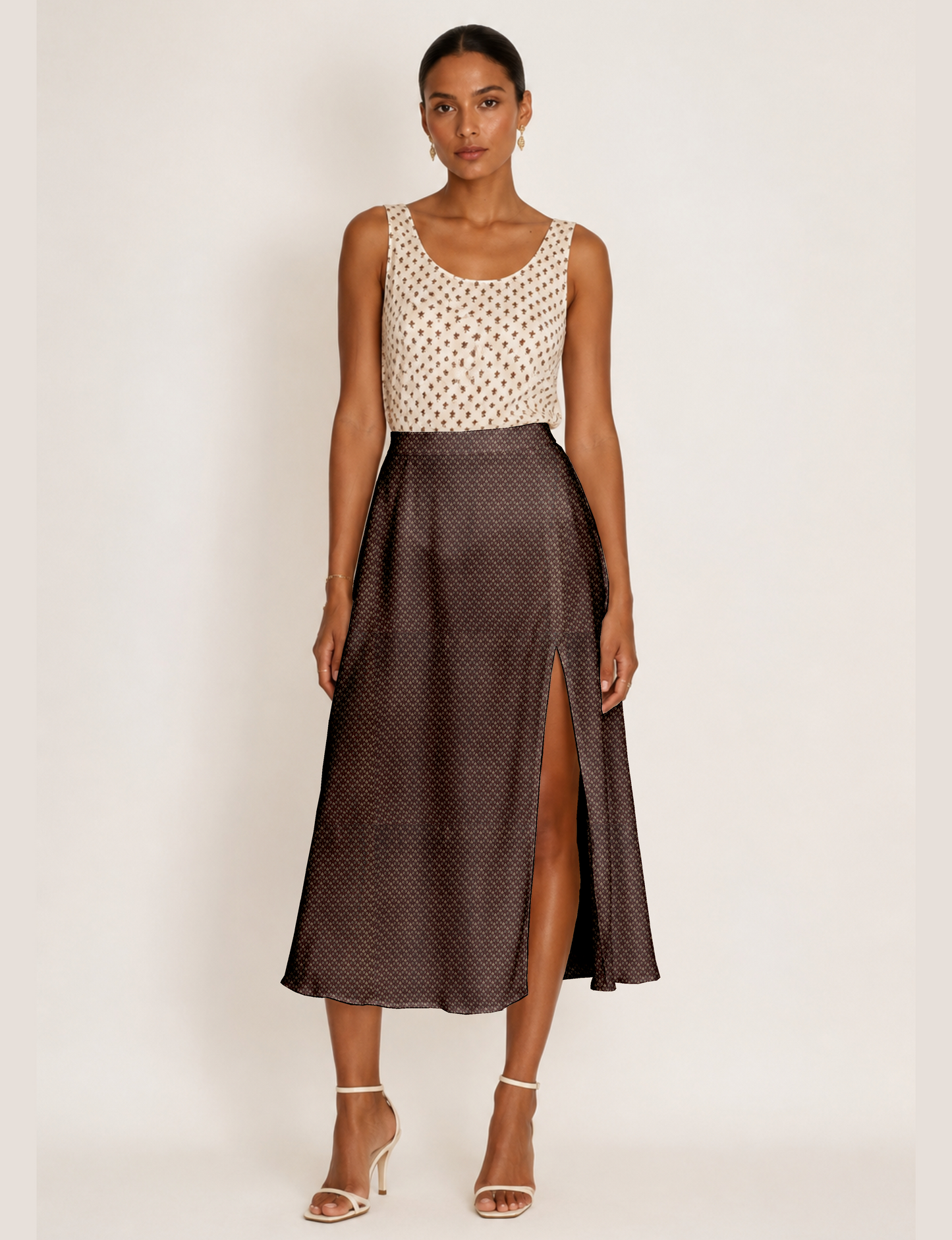 Woman wearing a yellow and black micro patterned A-line skirt with front slit, paired with beige sleeveless top and black
