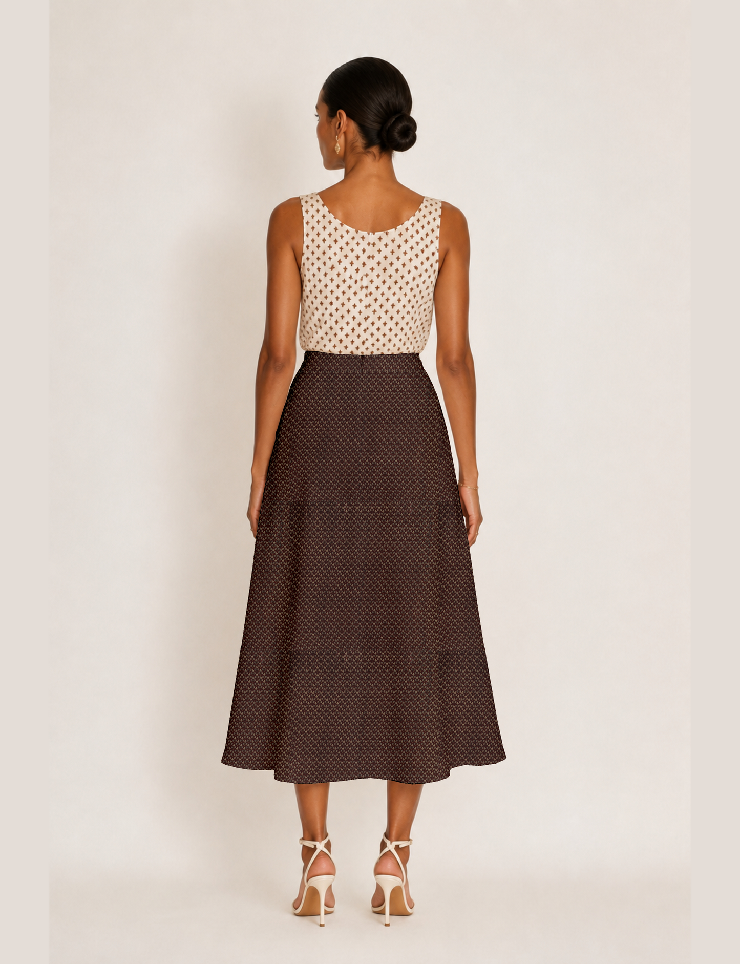 Woman wearing a yellow and black micro patterned A-line skirt with front slit, paired with beige sleeveless top and black