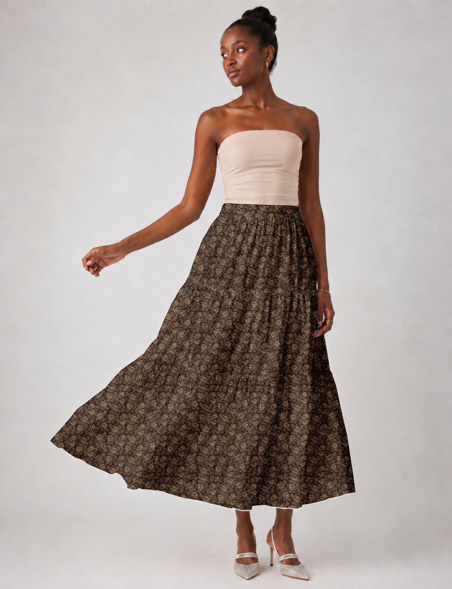 Woman wearing a yellow midi tiered skirt with a small geometric pattern, paired with a beige strapless top and white heels